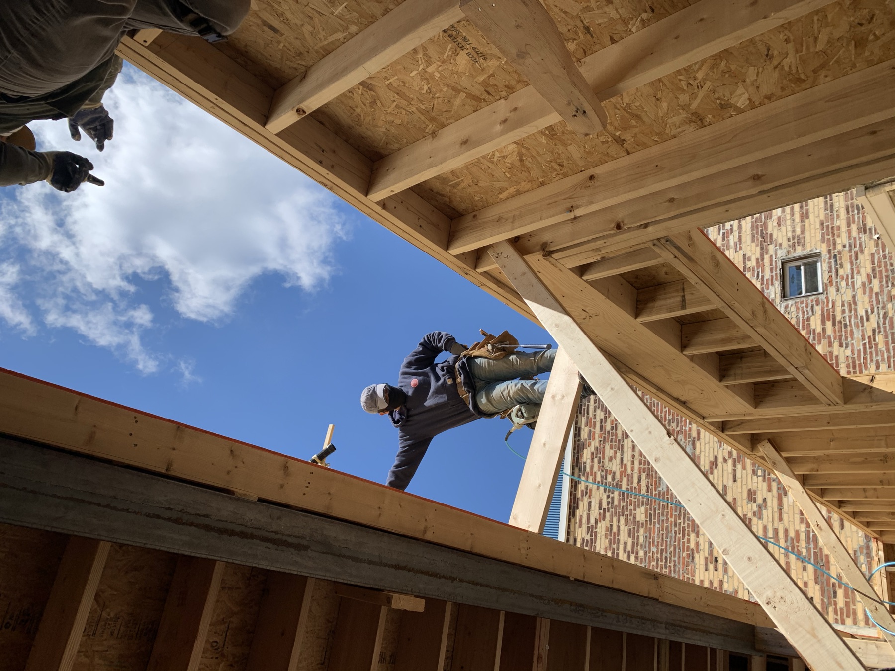 Paiz Builders carpenter setting the top plate on a framed wall against the Philadelphia sky