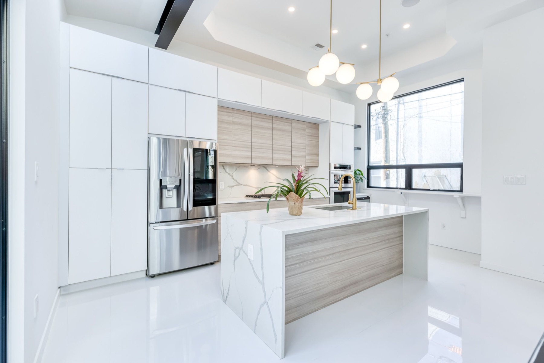 Custom white kitchen with waterfall quartz island remodeled by Paiz Builders in Philadelphia