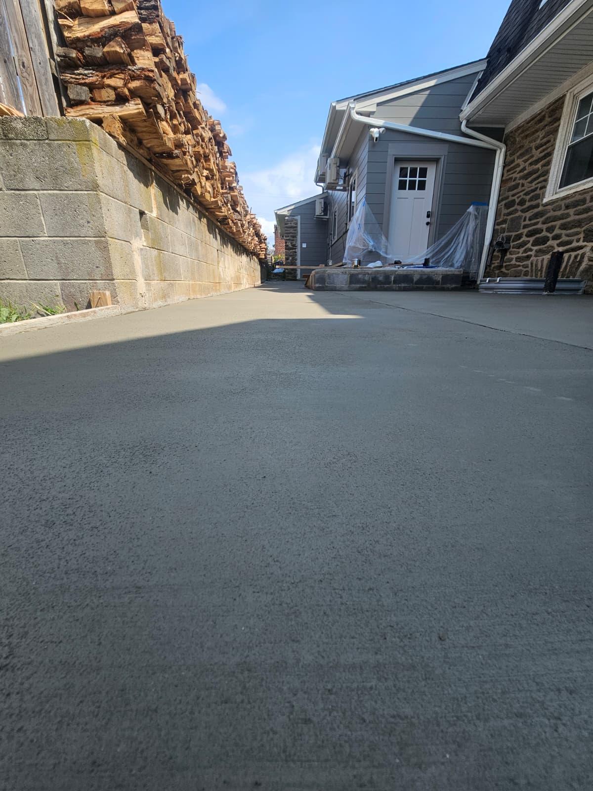 Concrete pad running to the rear entry of the stone house