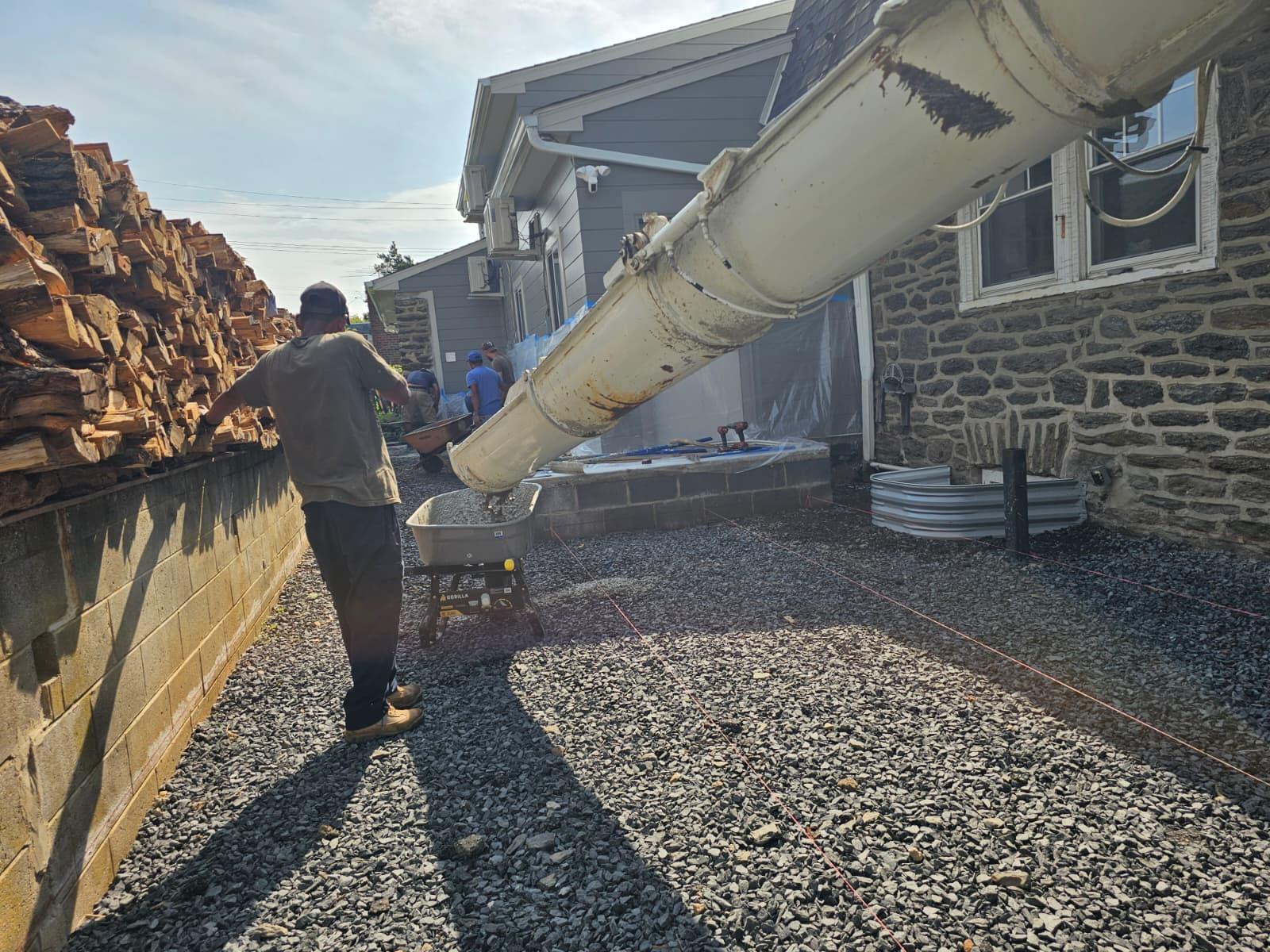 Concrete truck chute filling wheelbarrows over the compacted stone base