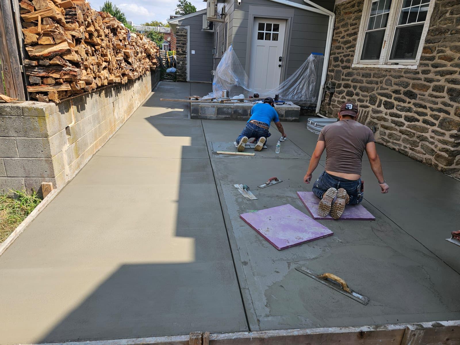 Crew hand-finishing the concrete slab from knee boards with trowels