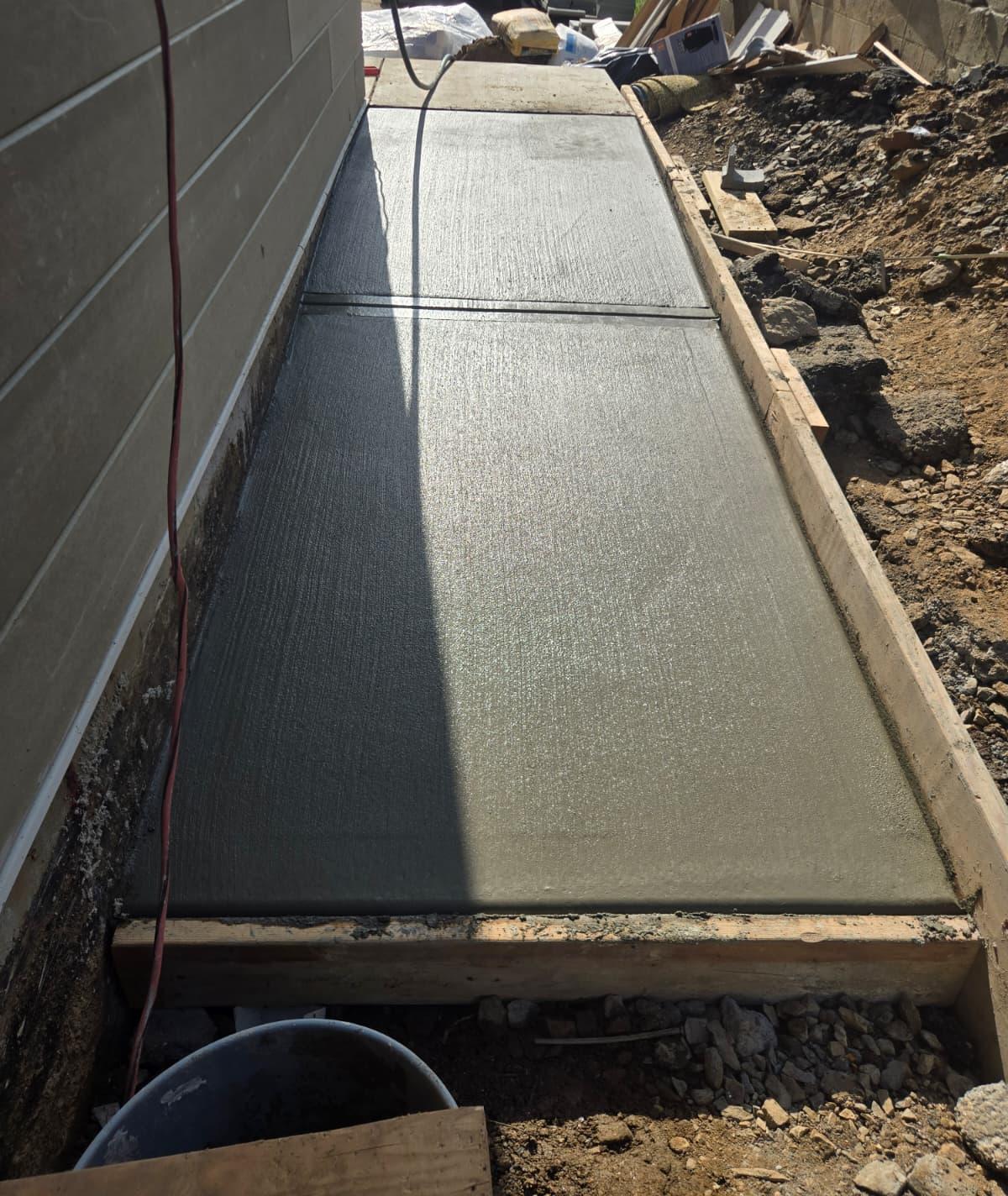 Broom-finished concrete side walkway with a tooled joint, still in its forms