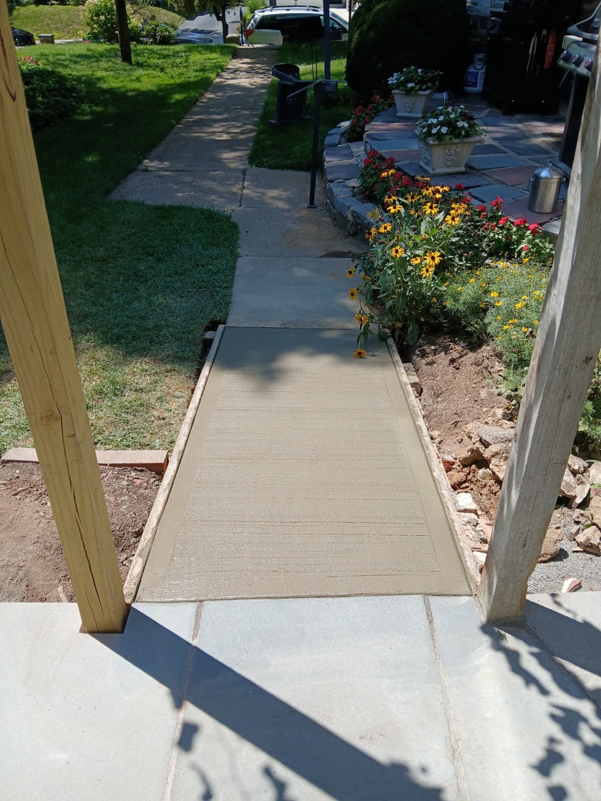 New concrete walkway meeting the flagstone patio and flower garden