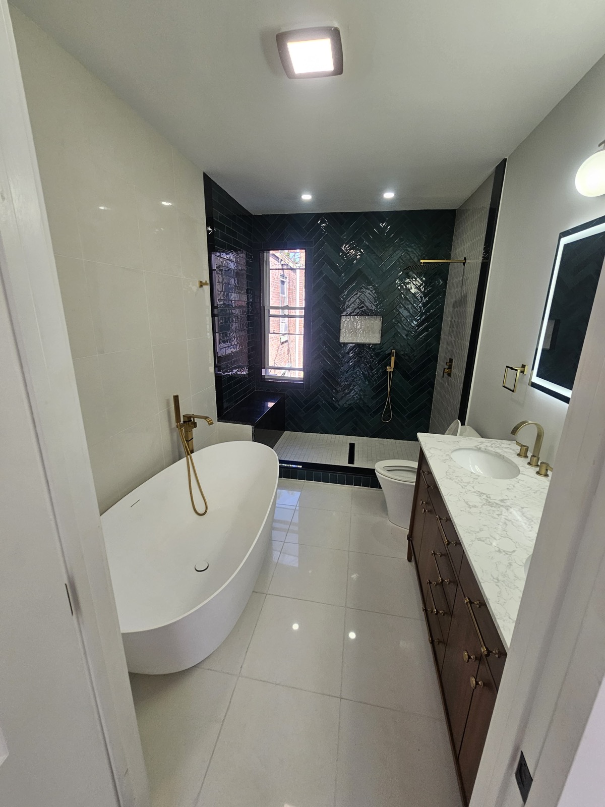 Designer master bath with green herringbone tile and freestanding tub
