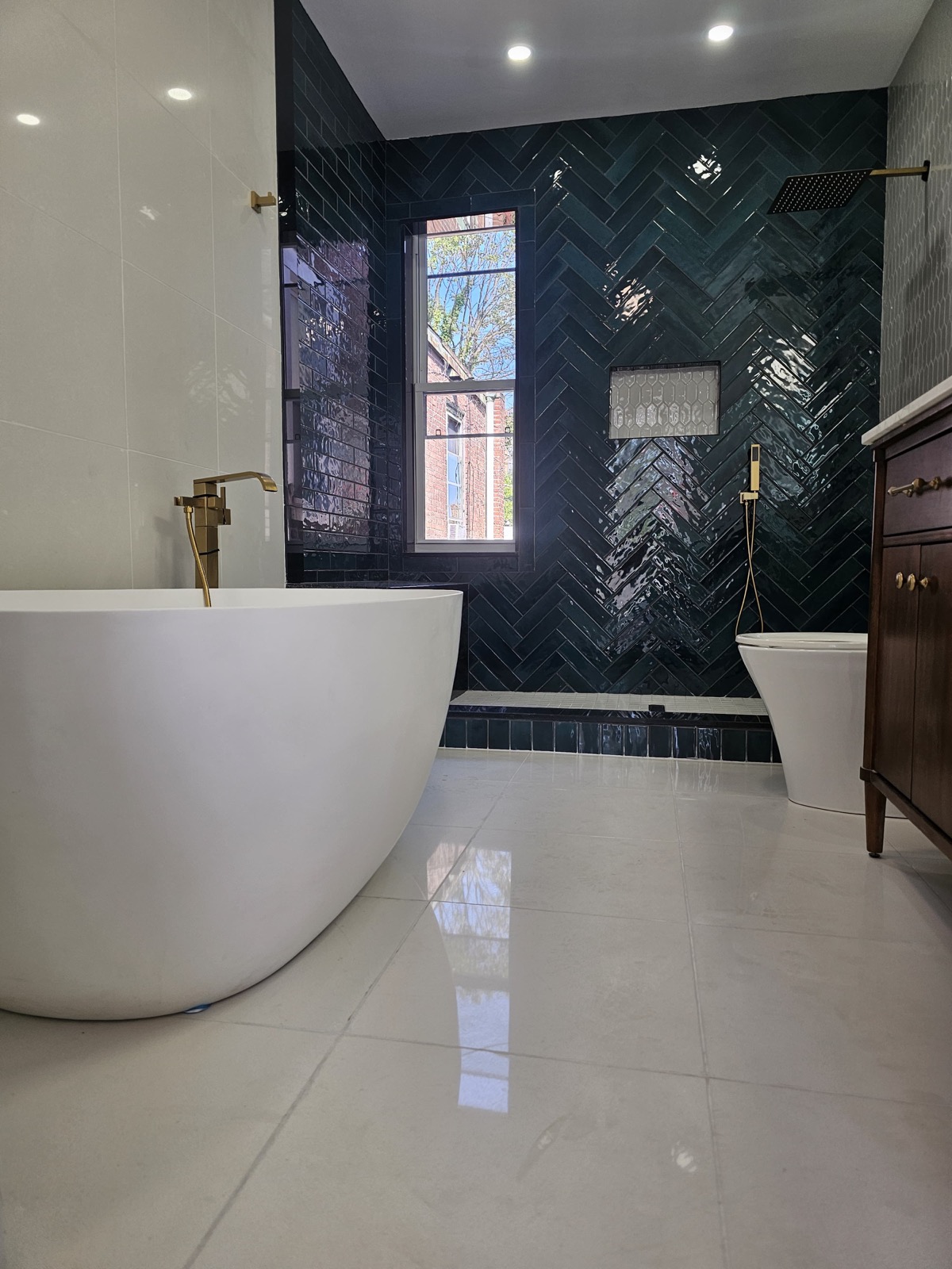 White tub with brass filler against green tile