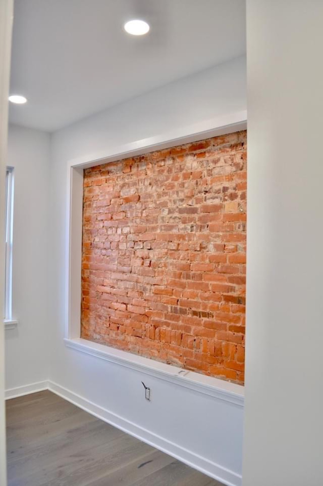 Framed exposed-brick accent niche in a white hallway wall