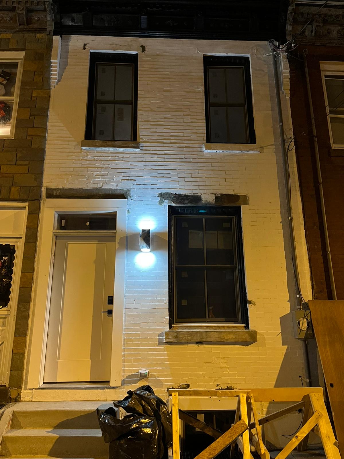 Night view of the finished white-painted brick facade with new sconce