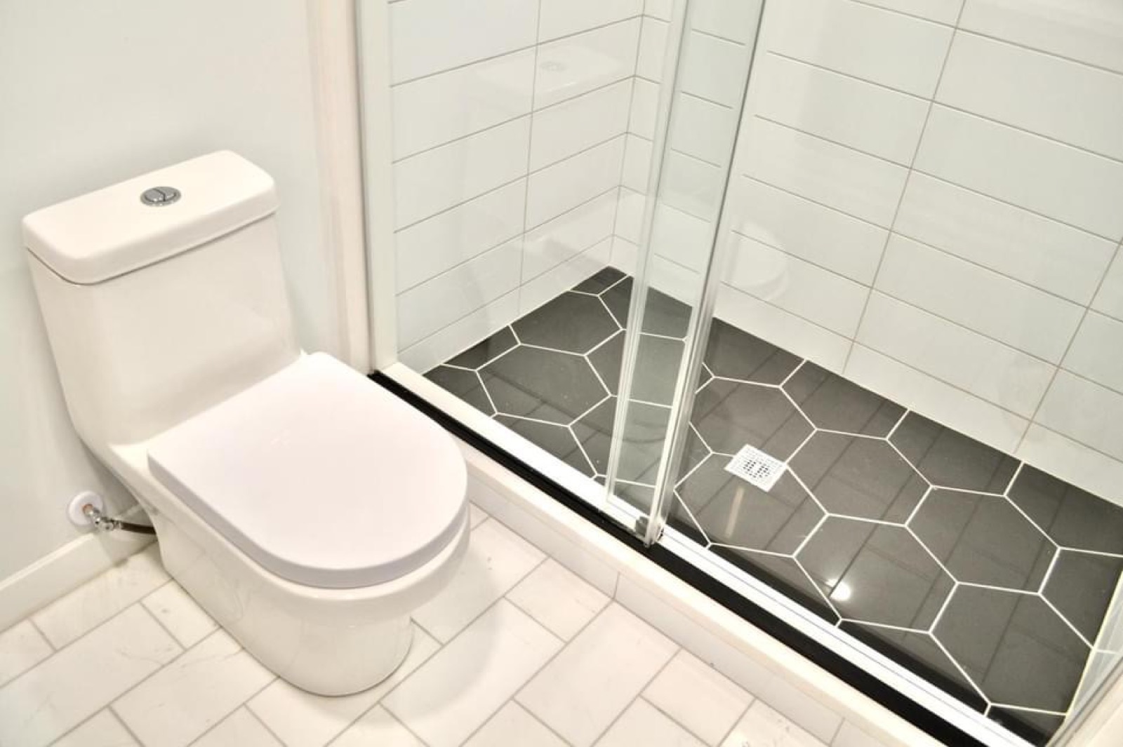 Glass shower with subway tile and charcoal hexagon floor