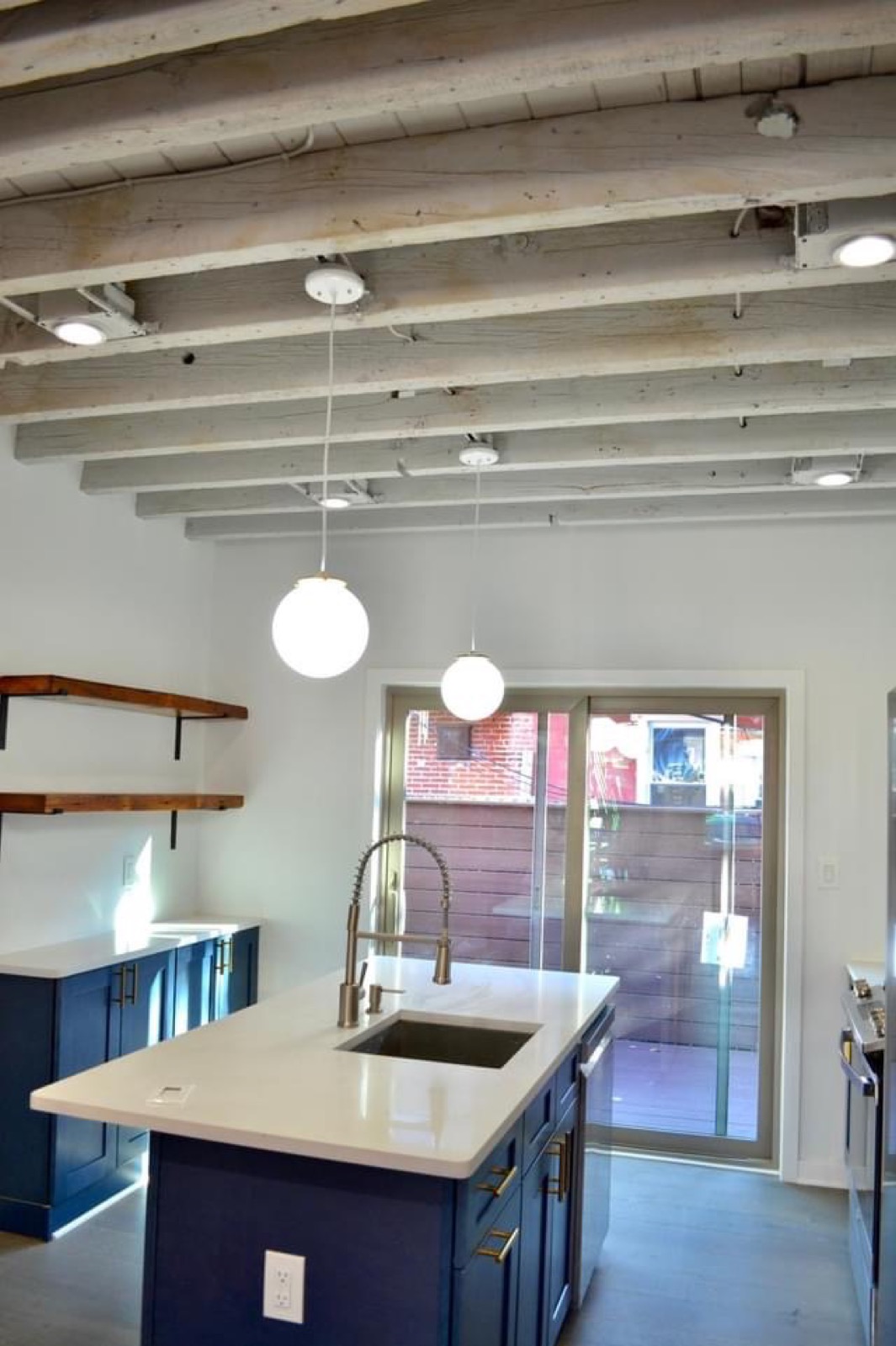 Kitchen island under exposed beam ceiling with patio door to the deck