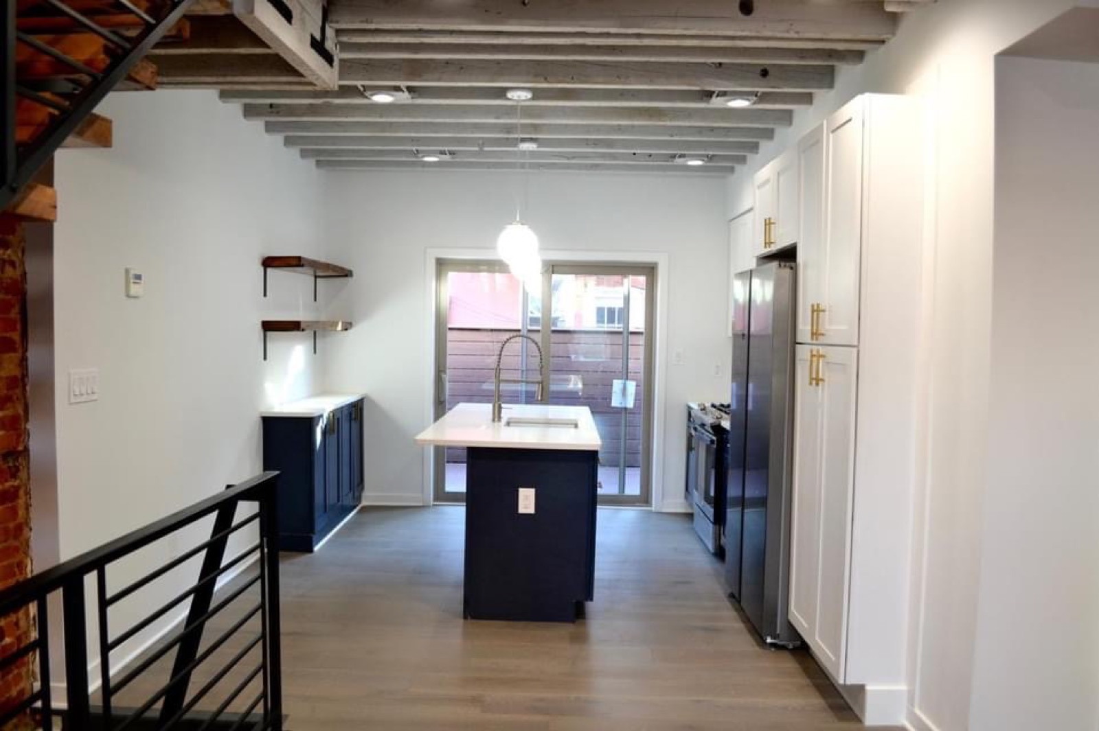 Navy island kitchen under whitewashed exposed joists in Kensington