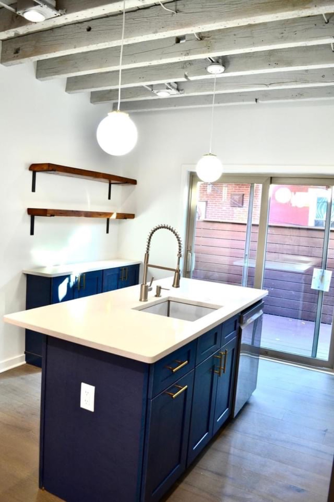 Navy kitchen island with globe pendants and coil faucet
