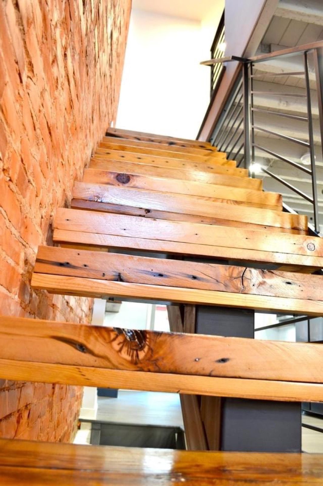 Open-riser reclaimed wood stair treads along the exposed brick wall