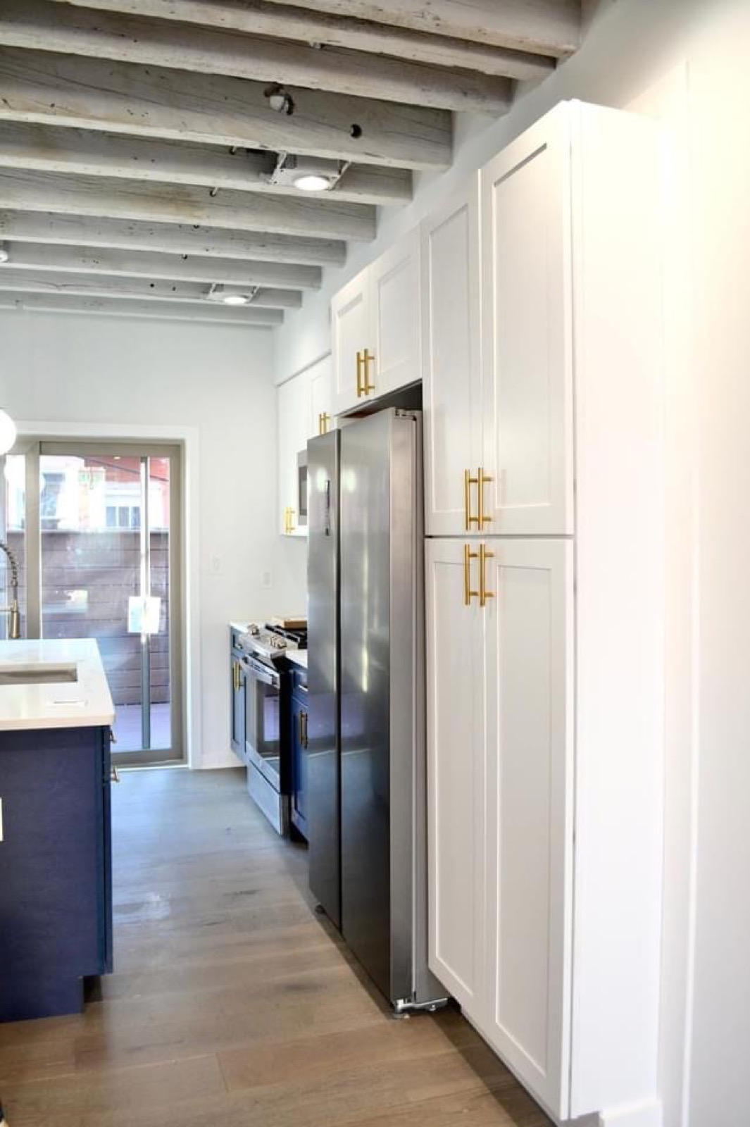 White pantry cabinets with brass pulls and stainless fridge