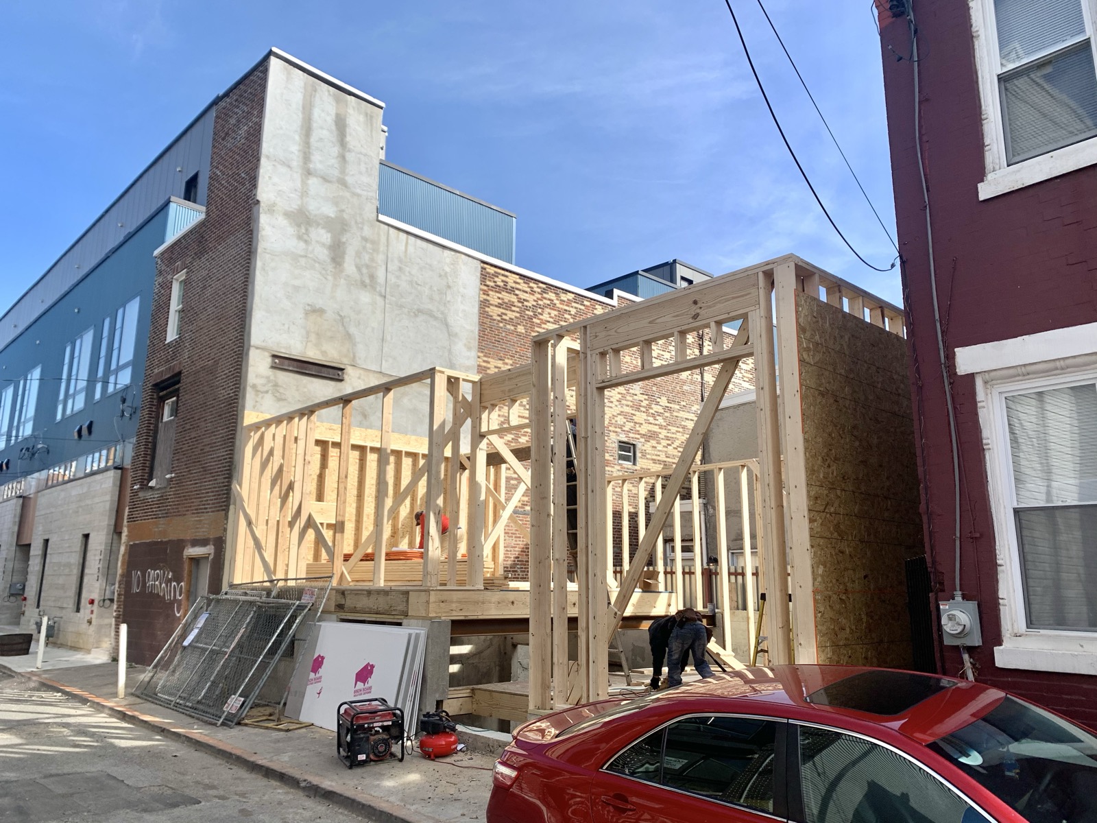 Framed addition rising between brick rowhomes