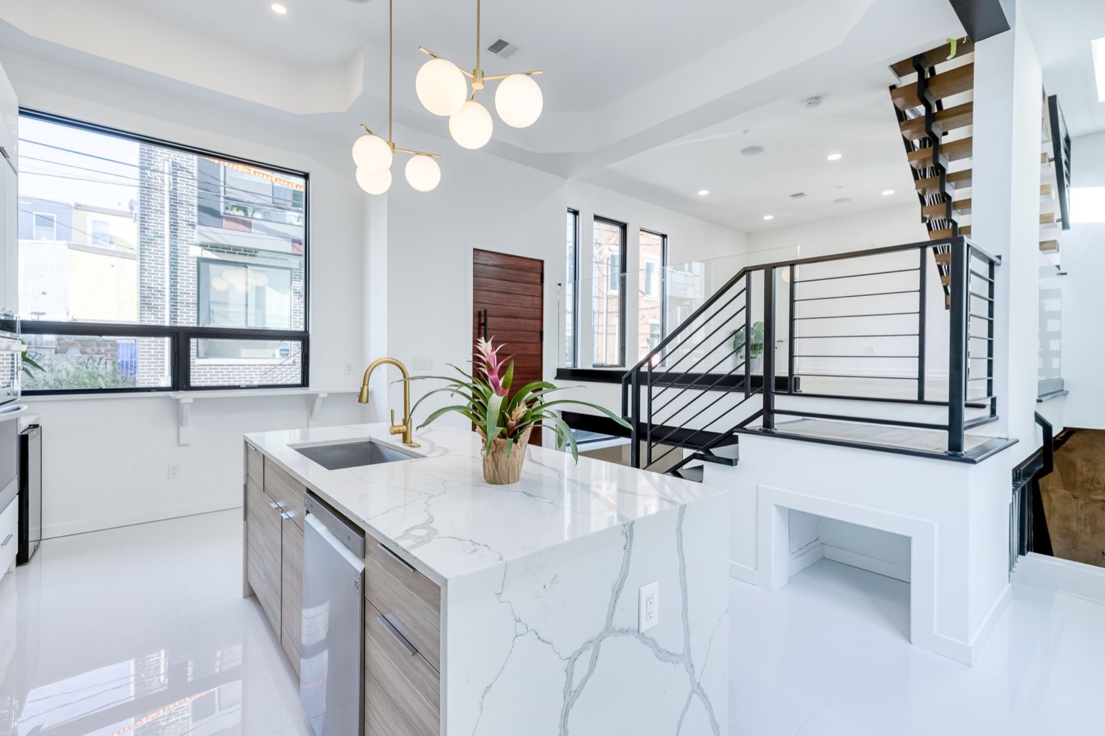Kitchen island with brass faucet beside the floating steel-and-wood staircase