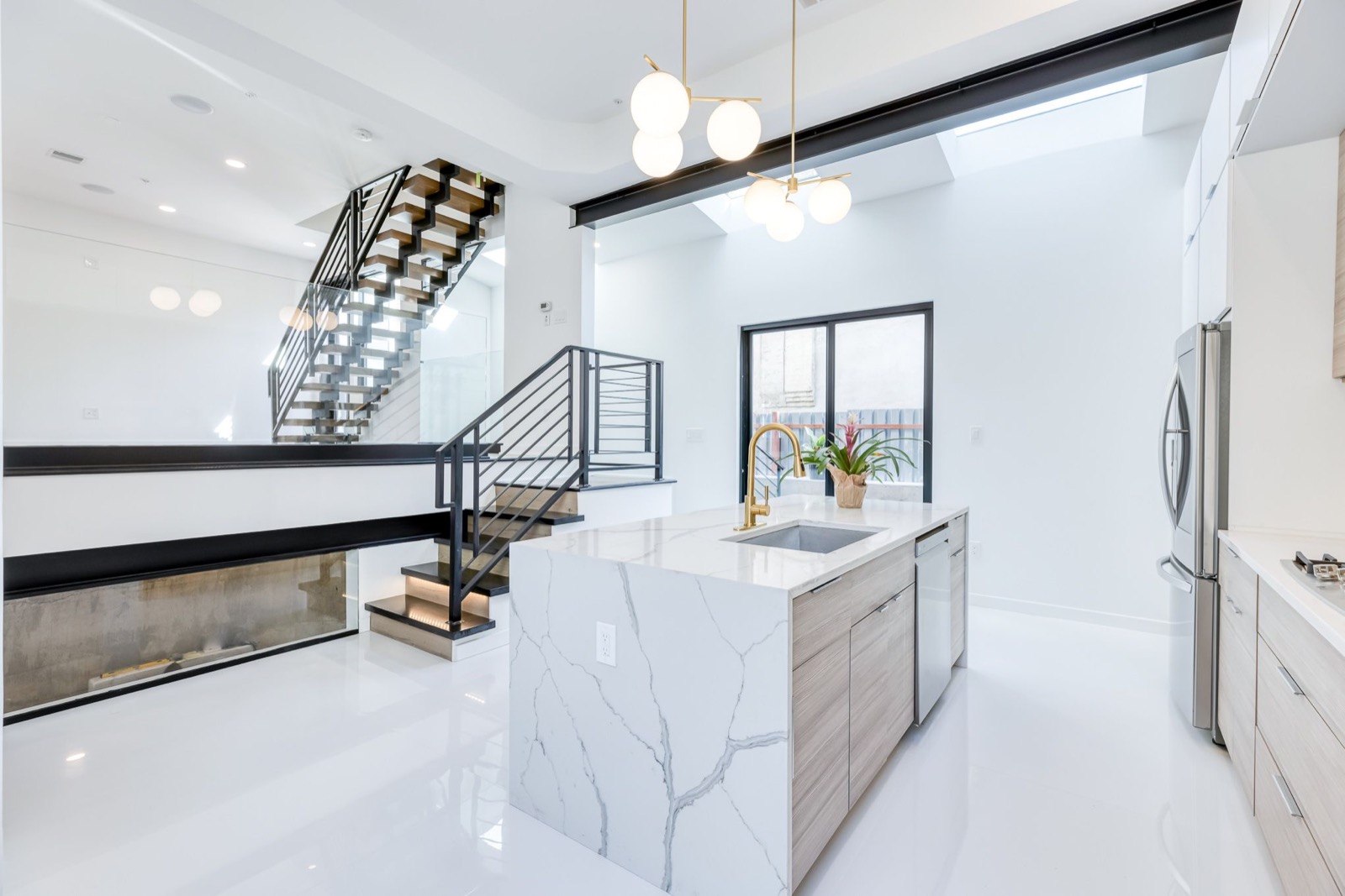 Open kitchen and stairwell under a skylight with double-sided fireplace