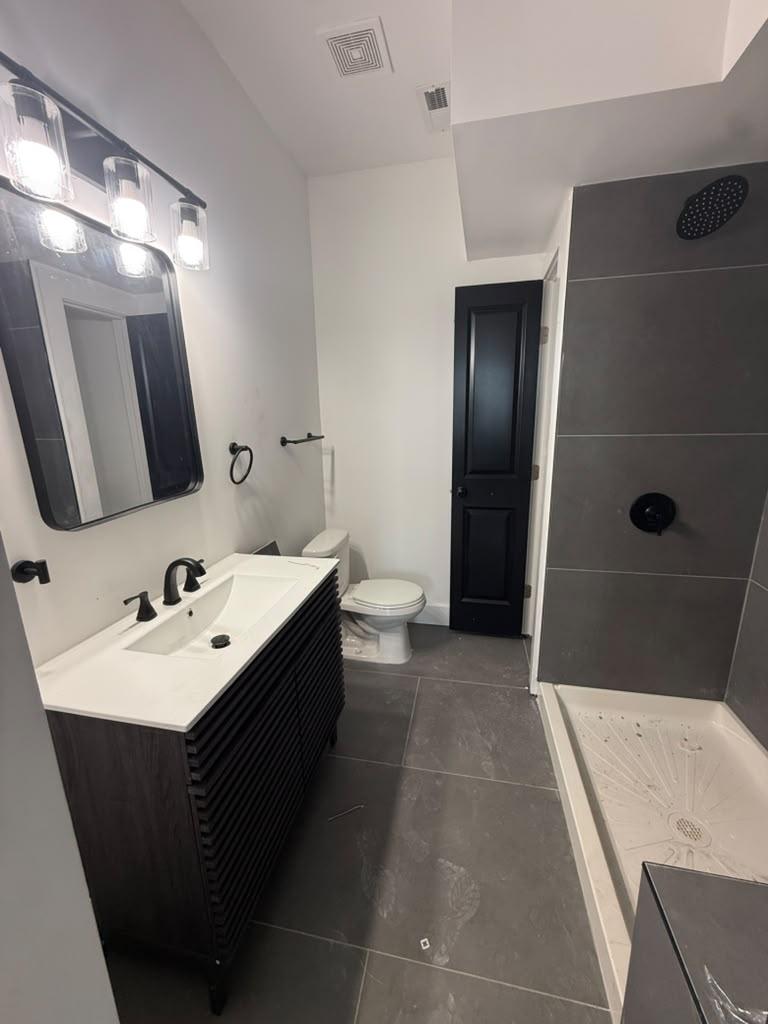 Bathroom with charcoal large-format tile, black fluted vanity, and walk-in shower