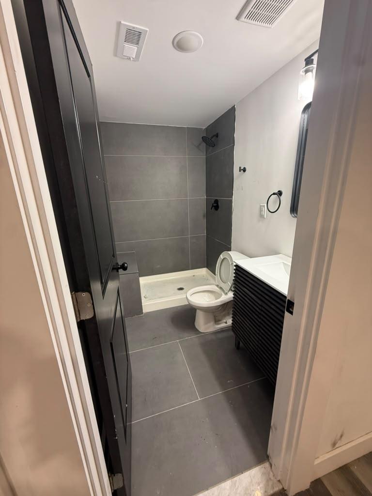 Walk-in shower with charcoal tile walls and a matte black rain shower head