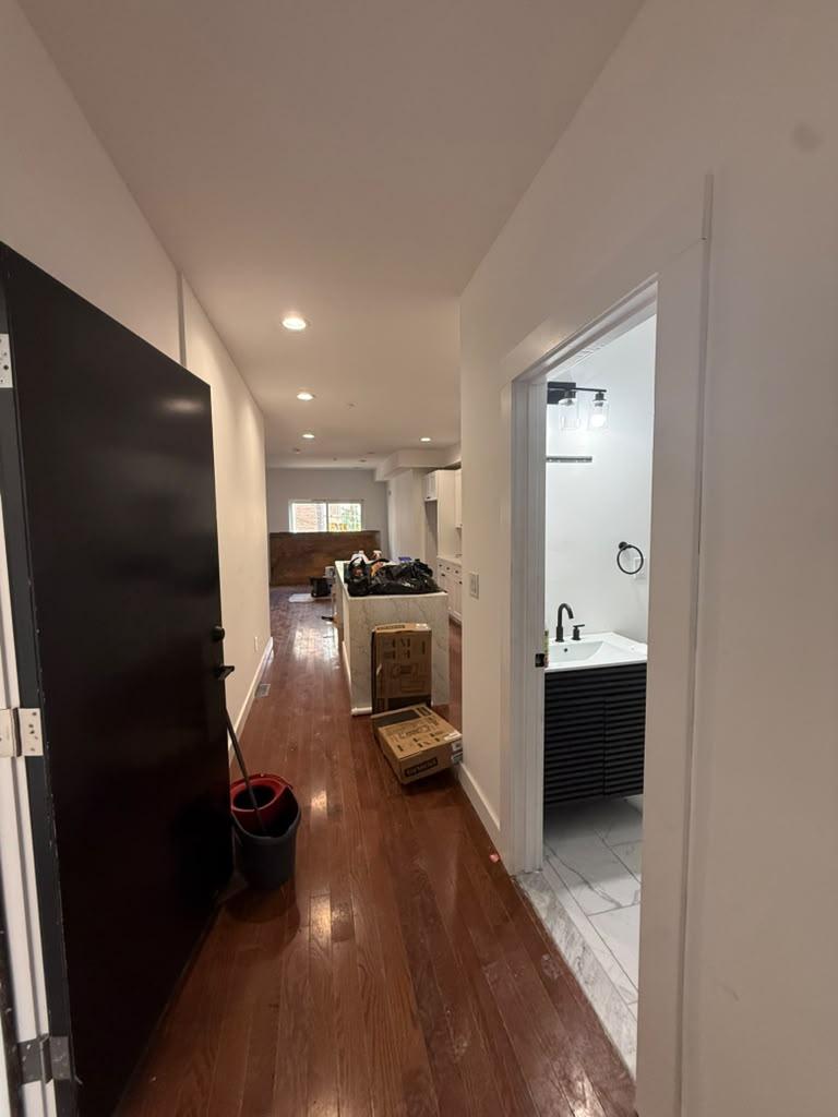 Hallway with hardwood floors and black doors opening to the renovated bathroom