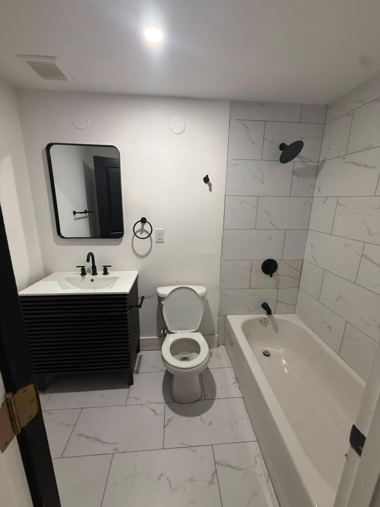 Bathroom with marble-look porcelain tile, tub, and matte black fixtures