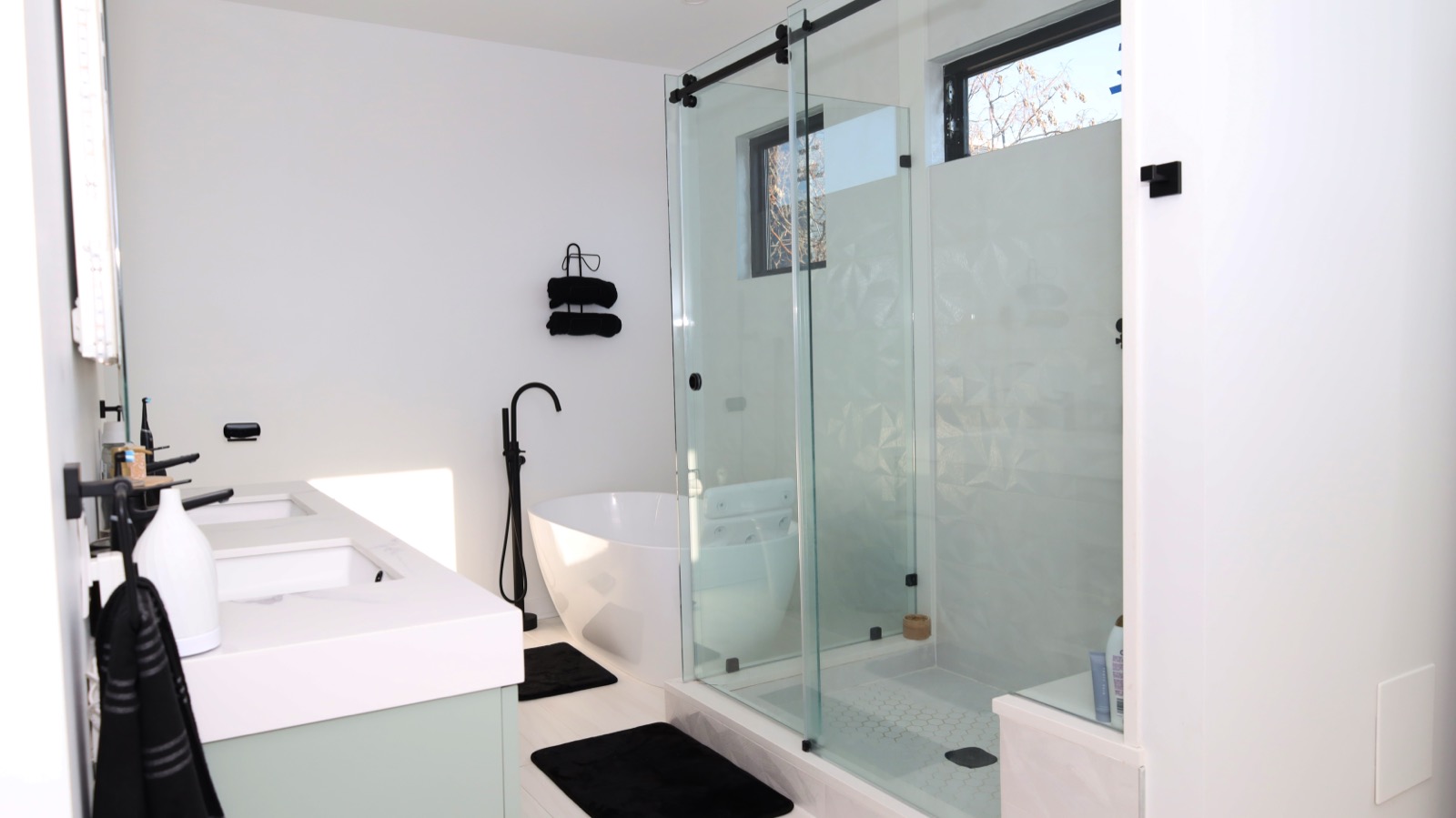Glass slider shower with black floor-mounted tub filler