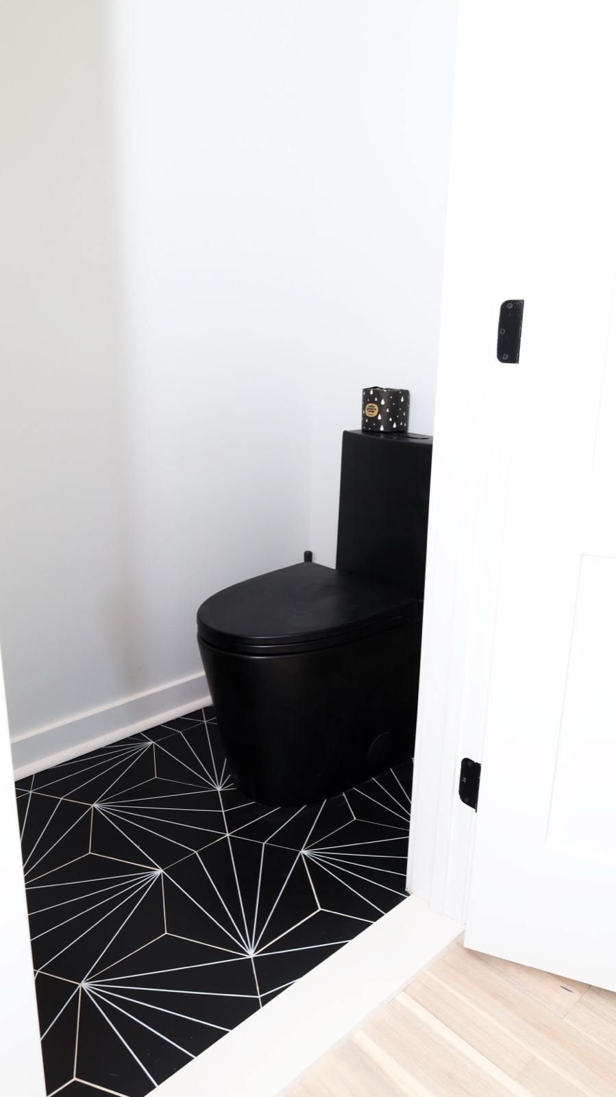 Powder room with matte black toilet and geometric starburst tile floor