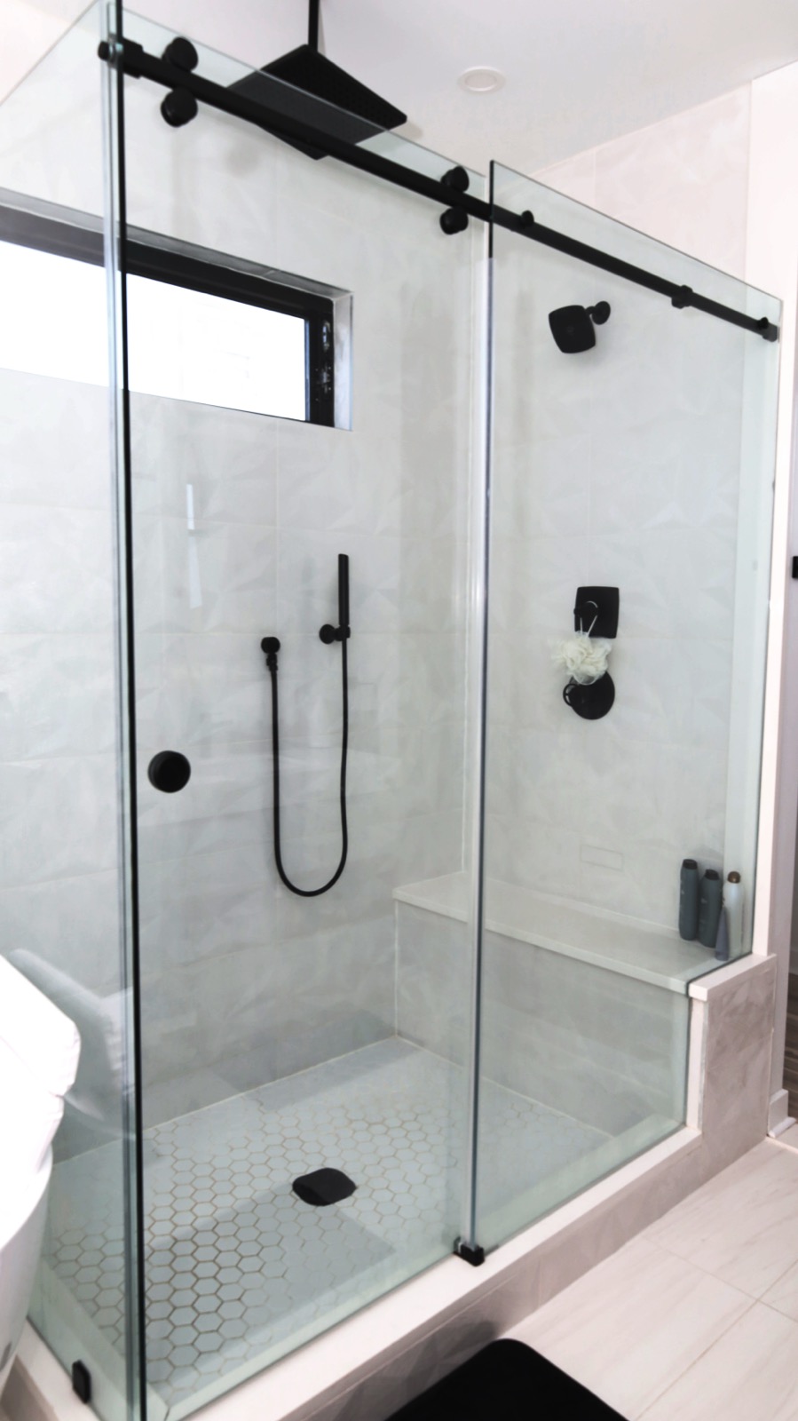 Textured white tile shower with bench and matte black rain fixtures