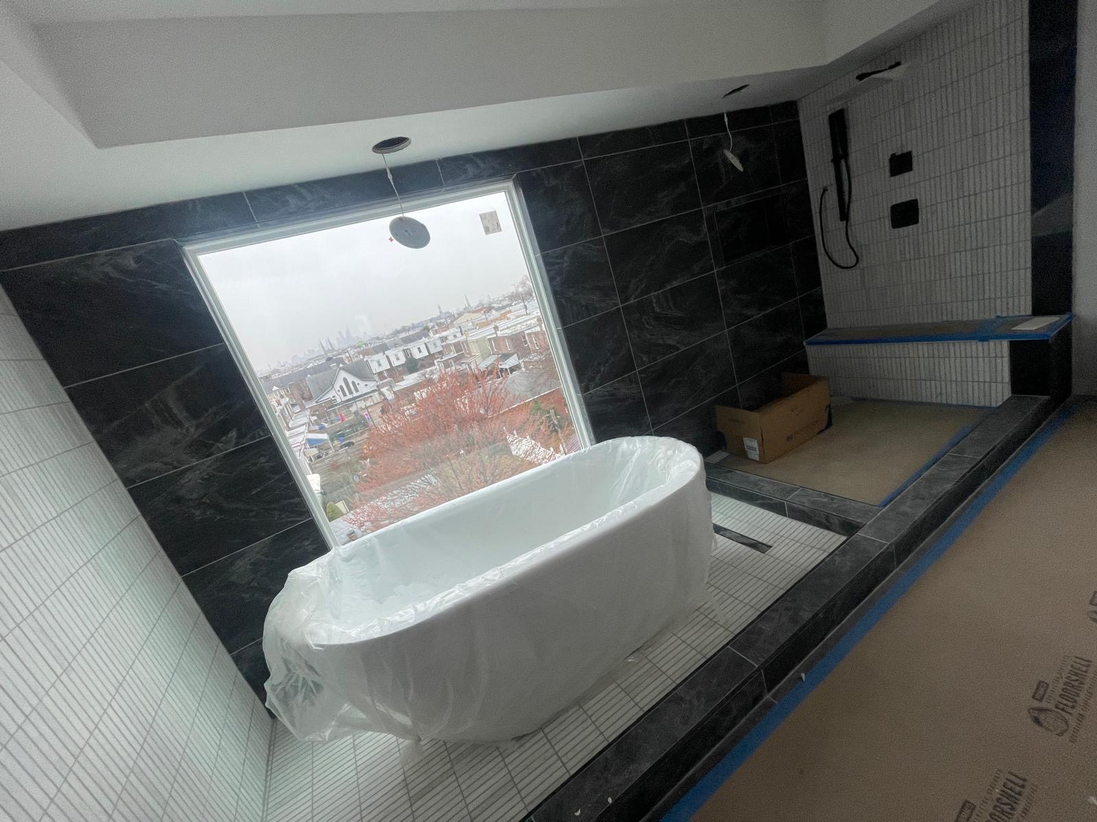 Freestanding tub with black marble tile and a Philadelphia skyline view
