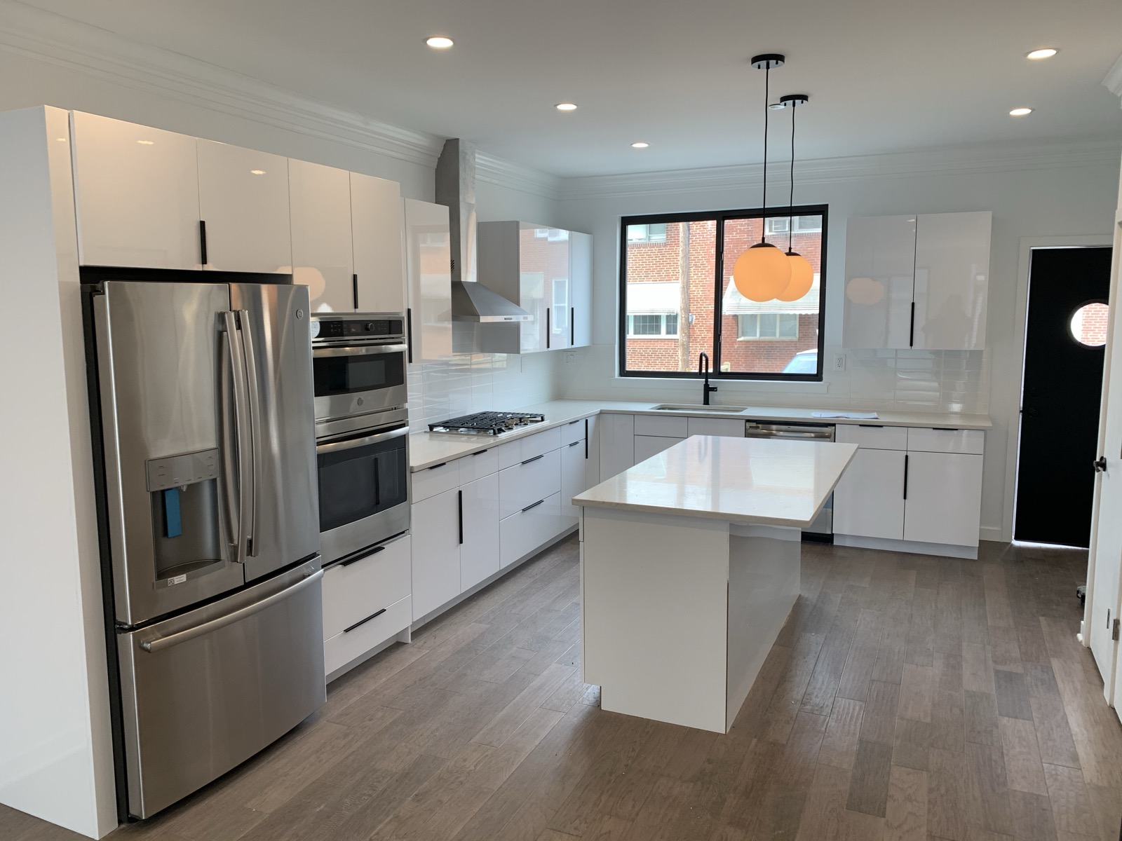 Gloss white kitchen with quartz island and stainless fridge