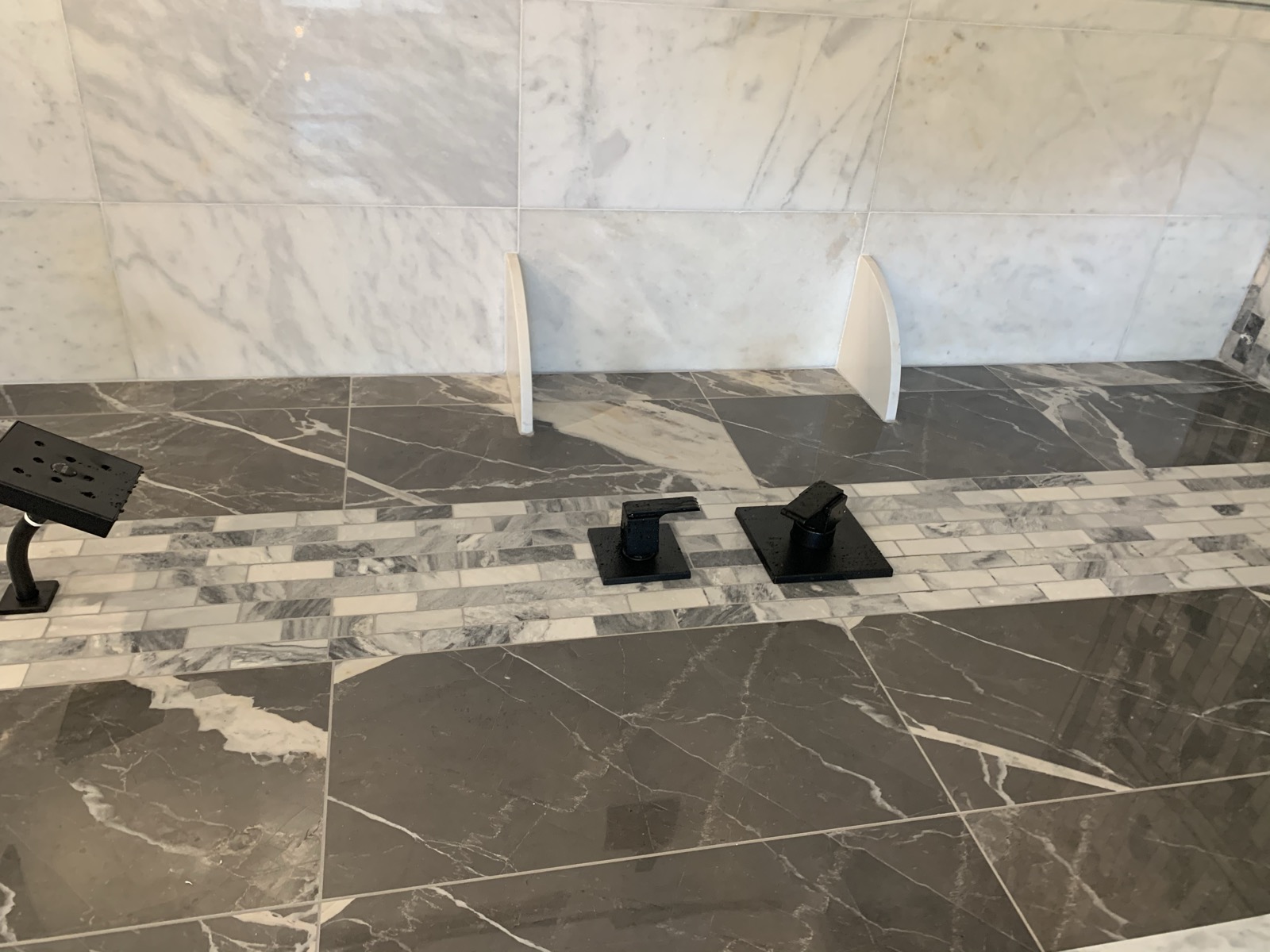 Shower detail with gray marble tile and mosaic accent band