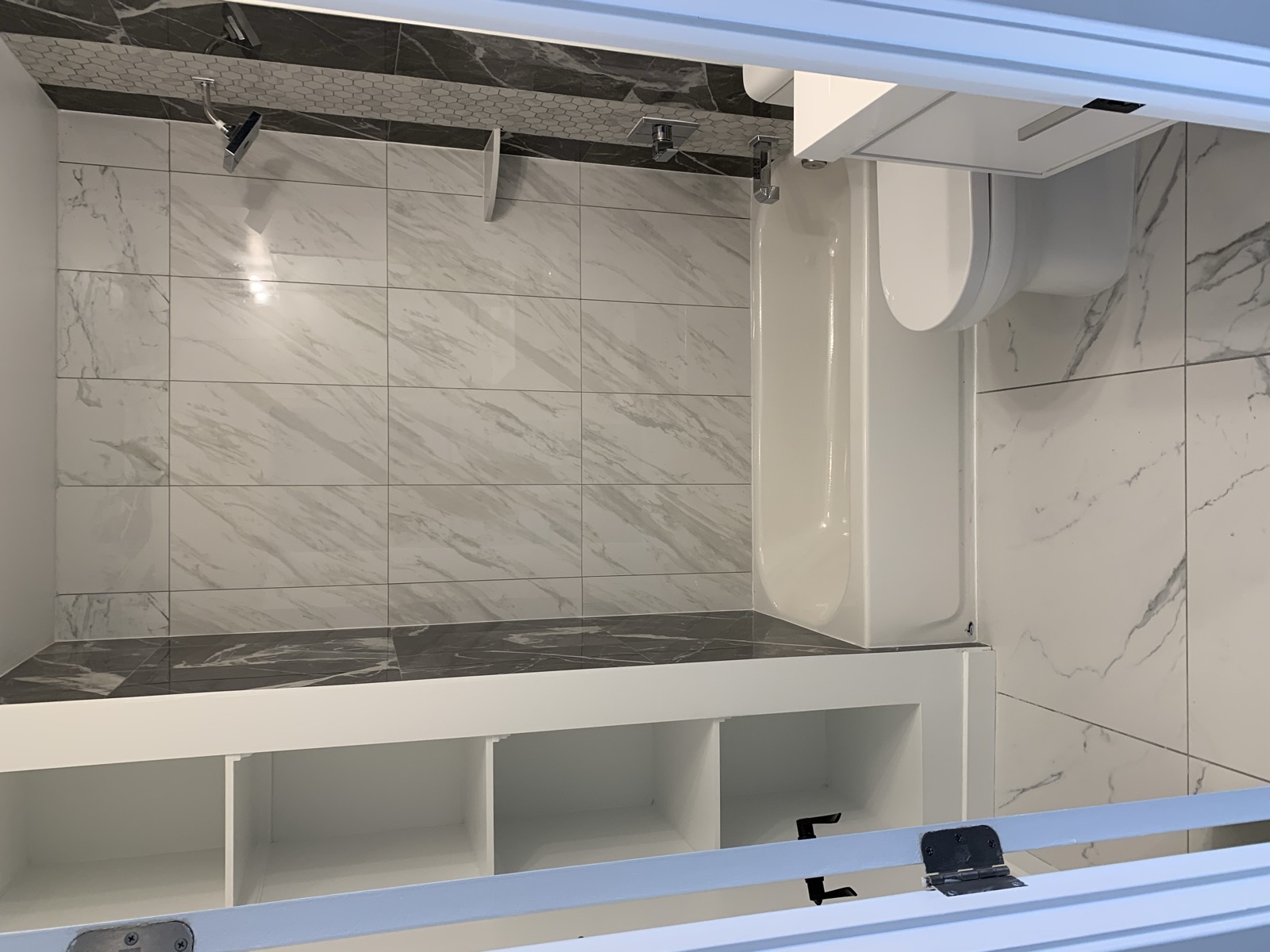 Tub shower with marble-look tile and hex accent strip