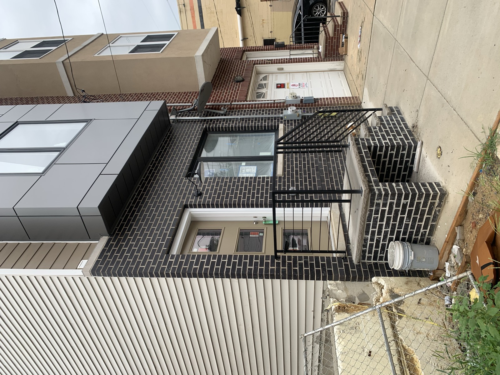 Street-level entry with black brick, concrete stoop, and metal railings