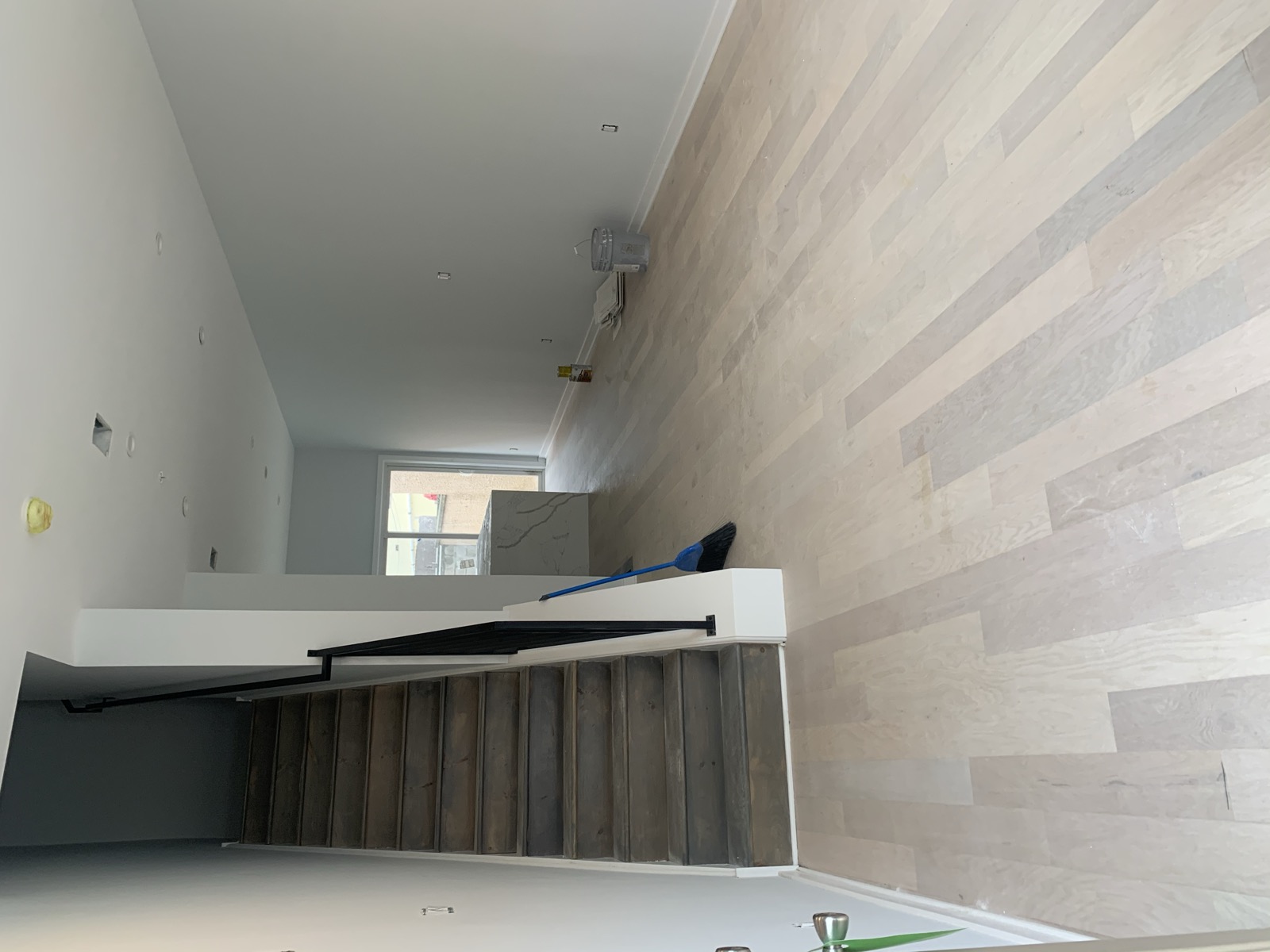 Main living area with dark-stained stairs and whitewashed oak floors