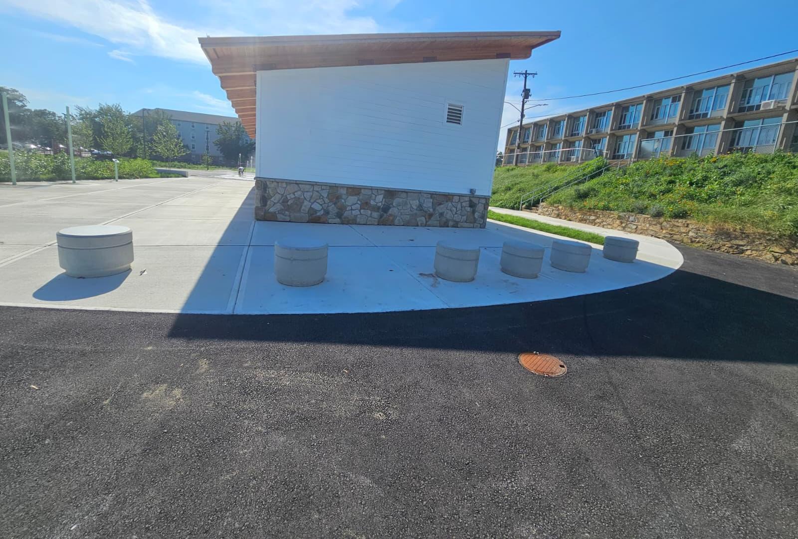 Curved concrete edge meeting new asphalt at the end of the building