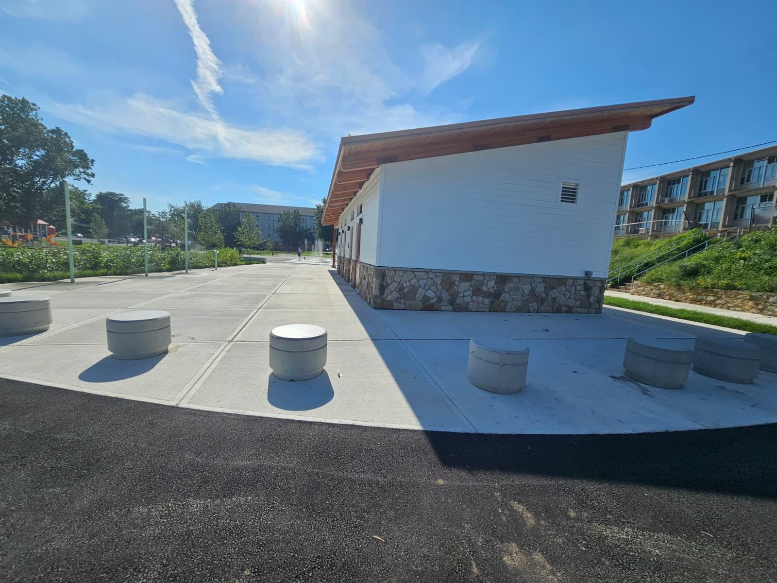Curved concrete pad with round precast bollards at the end of the building