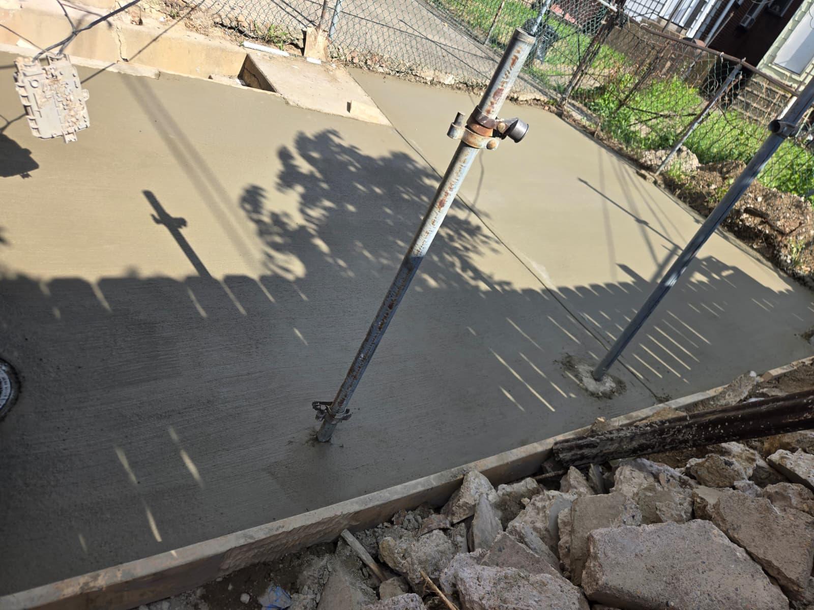 Freshly poured broom-finished concrete pad in a rowhome back yard