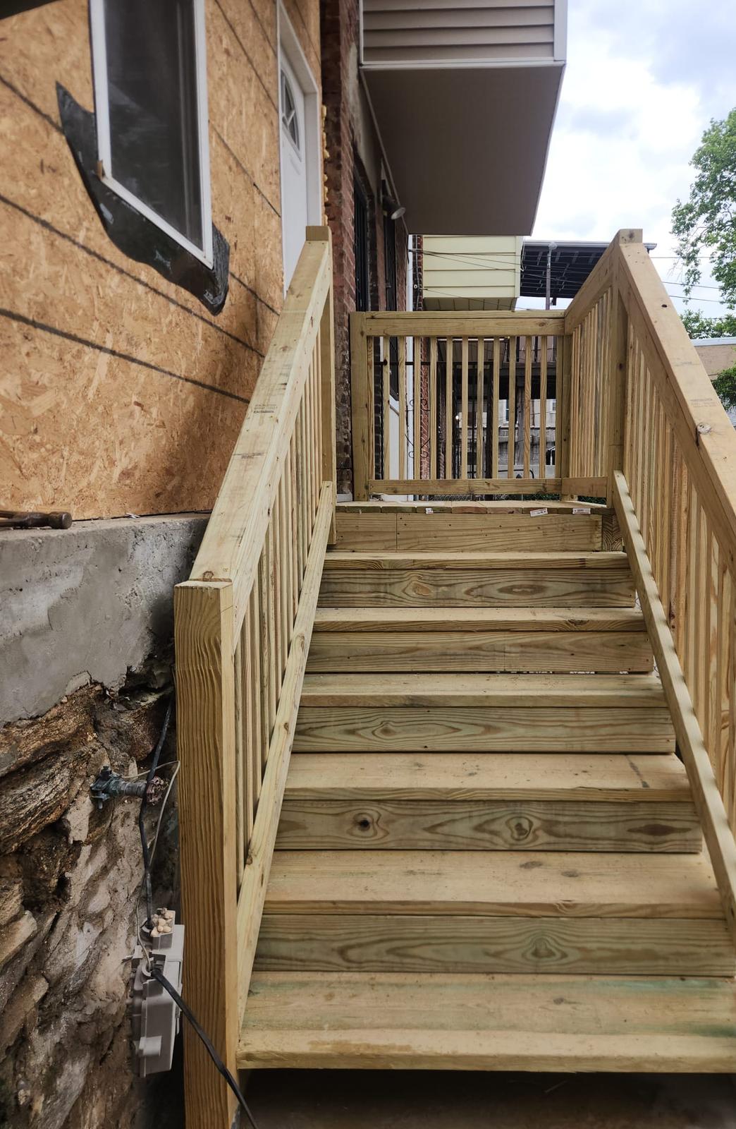 Pressure-treated wood stairs with balusters leading up to the rear door landing