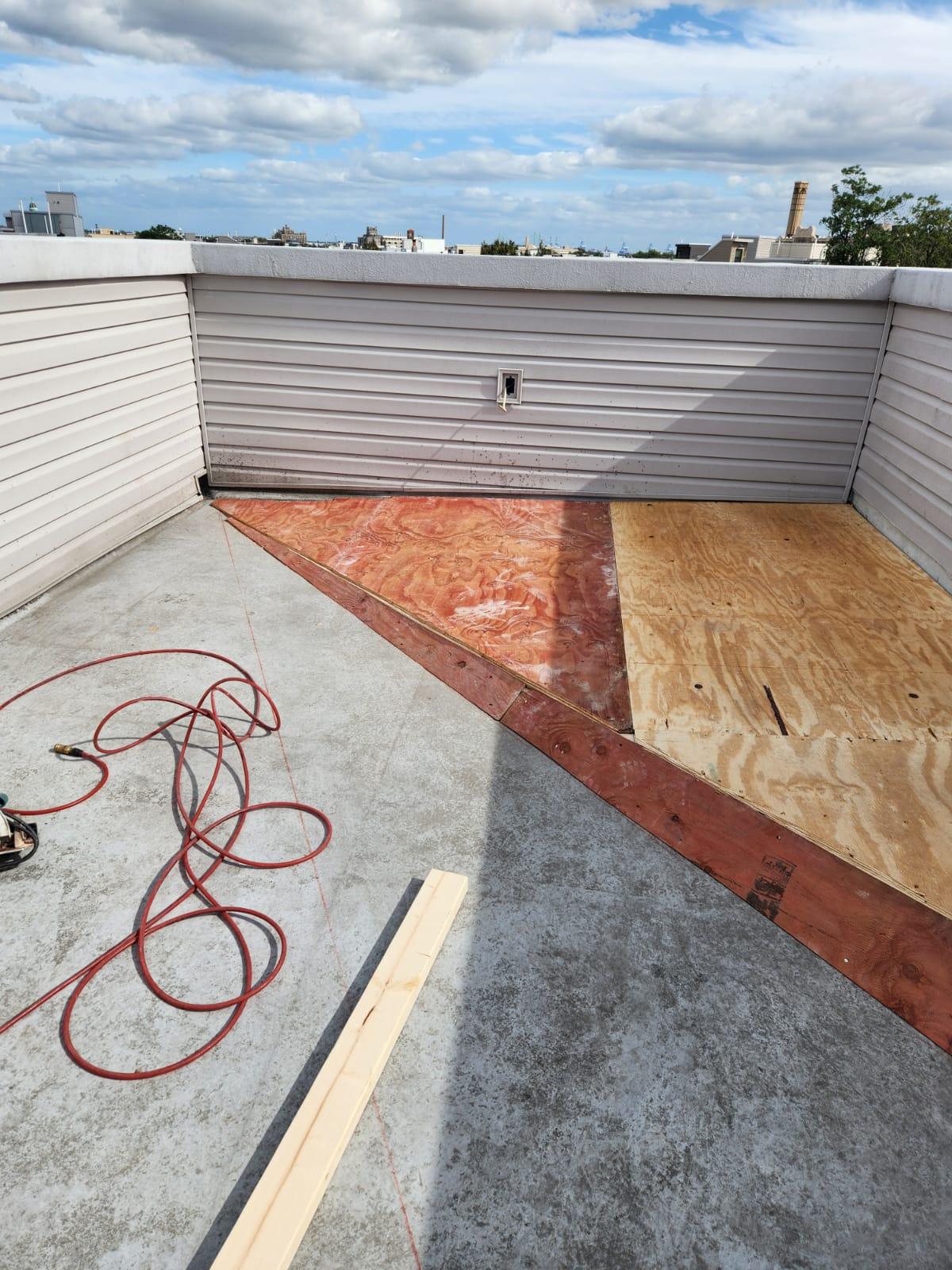Roof deck corner platform framed and sheathed in plywood, with the skyline beyond the parapet