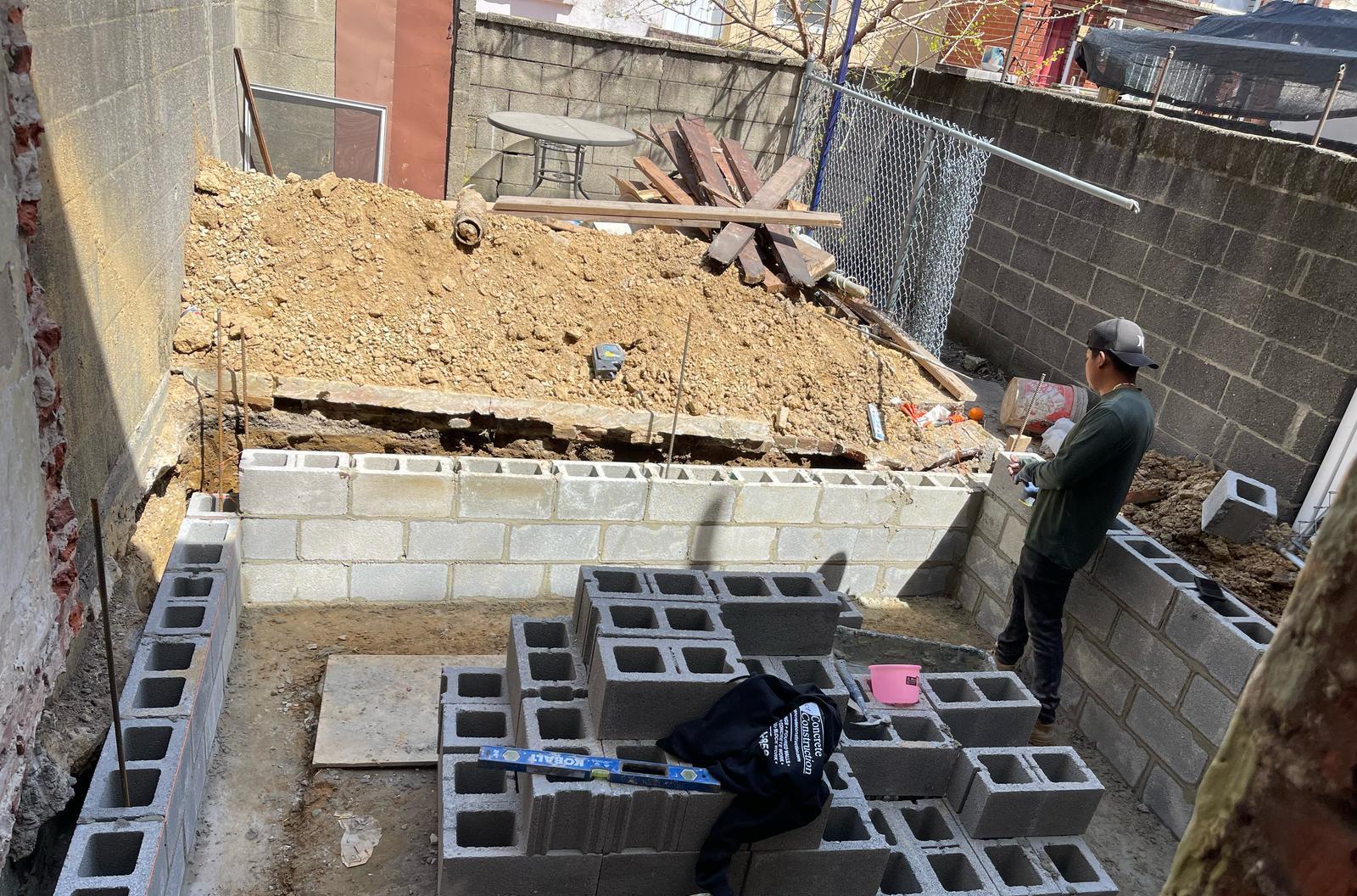 Mason laying CMU block foundation walls for a rowhome rear addition