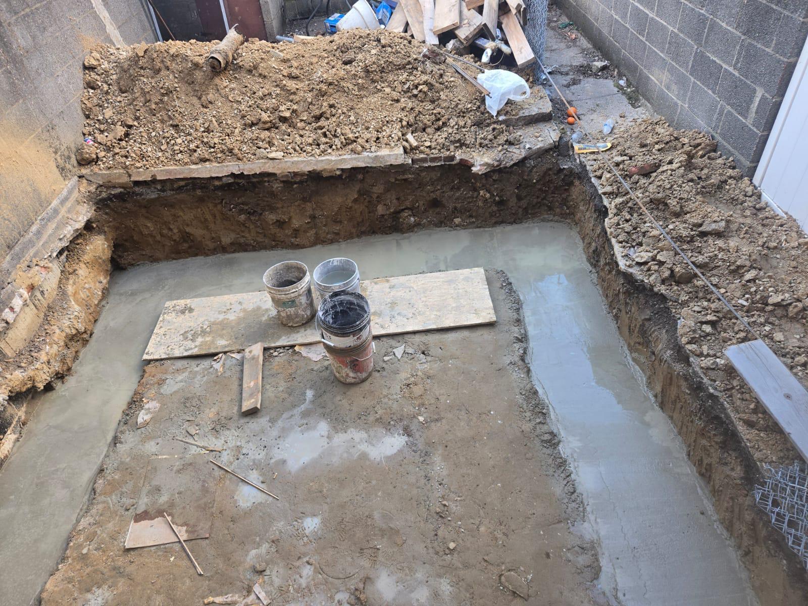 Freshly poured footing in the excavated rear yard of a rowhome
