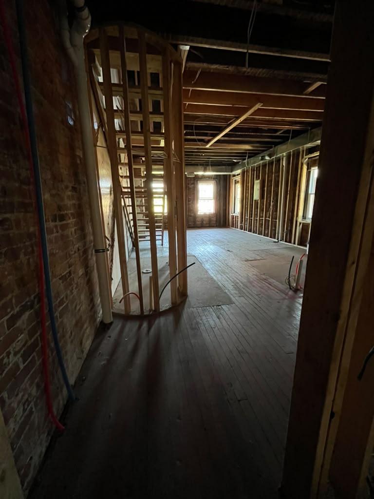 Curved stair enclosure framed beside an exposed brick party wall