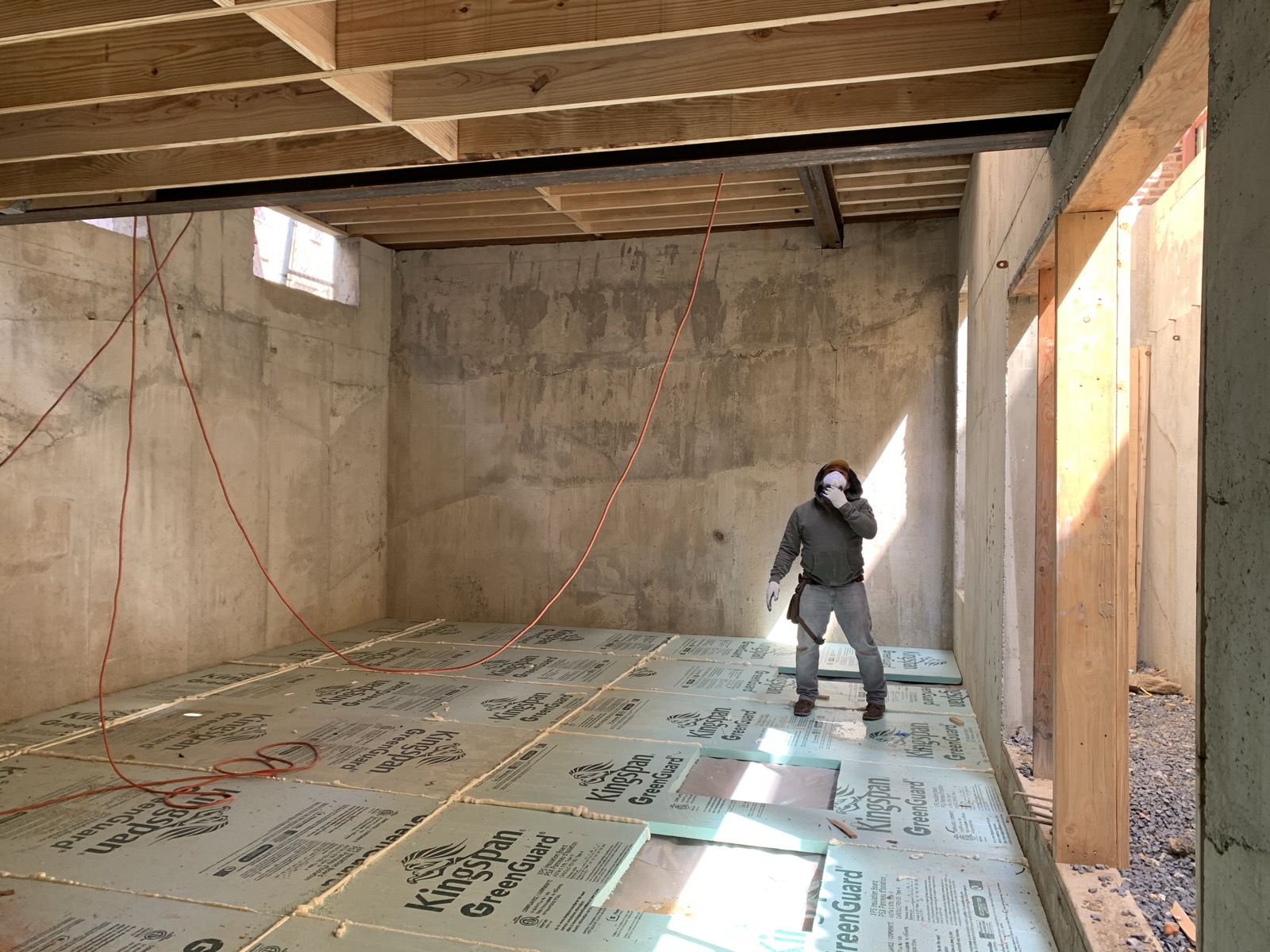 Rigid foam insulation over a basement slab between concrete walls