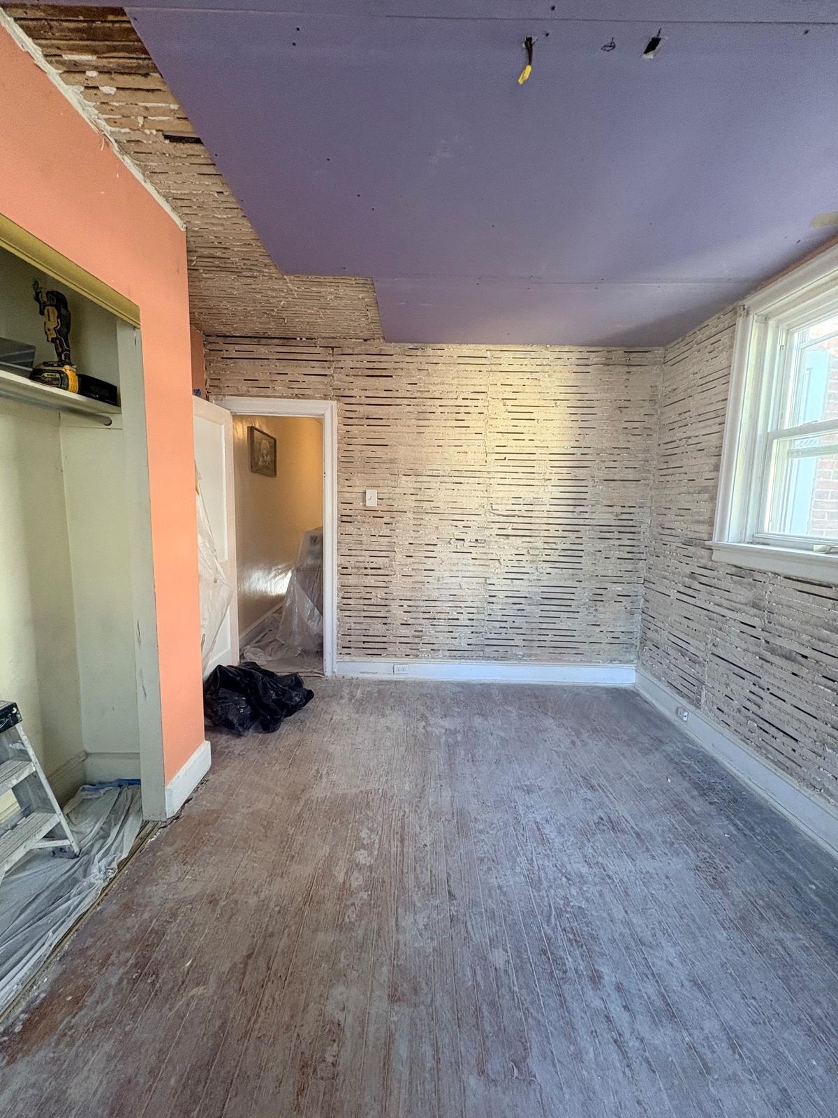 Before: bedroom walls stripped to wood lath with a new drywall ceiling hung