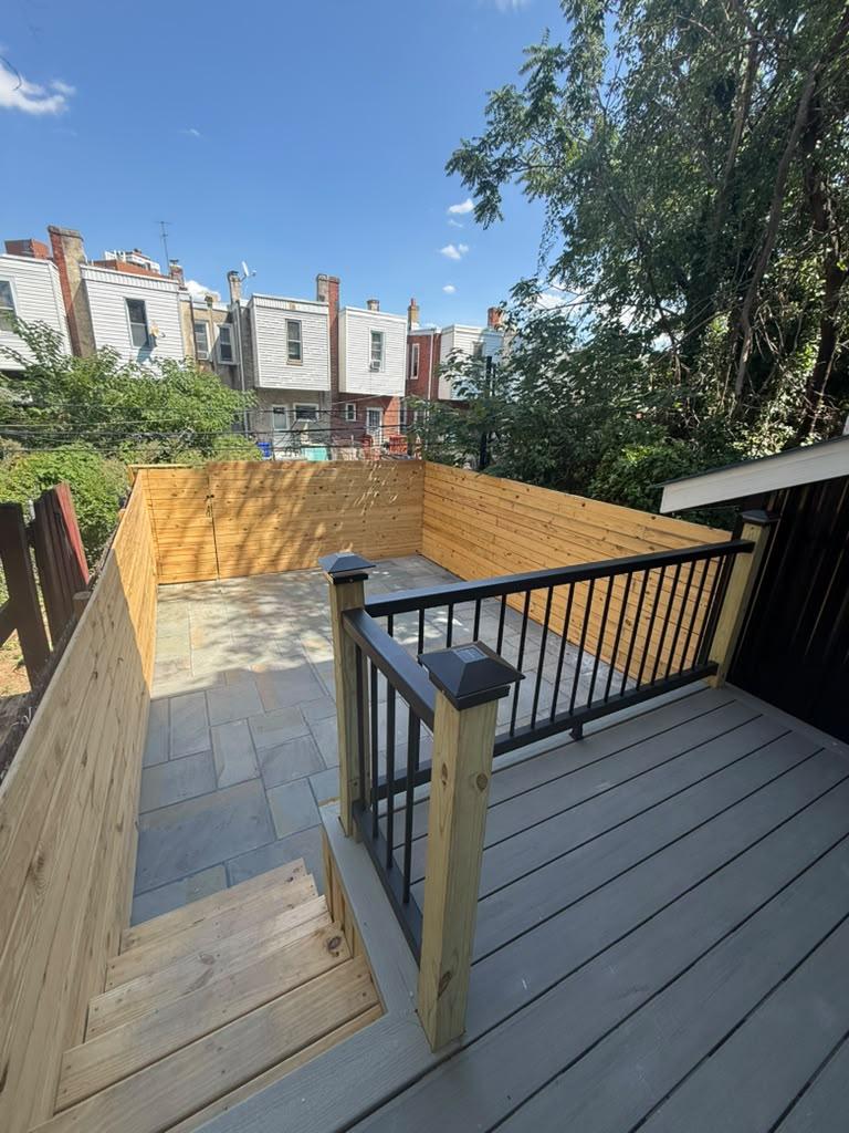 Composite deck with black railing stepping down to a fenced bluestone patio