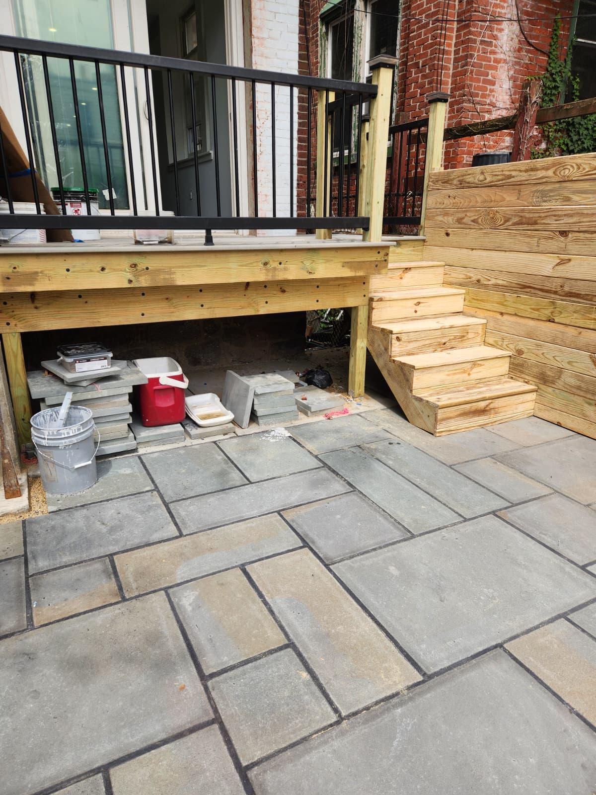 Deck with black railing and steps down to the bluestone patio