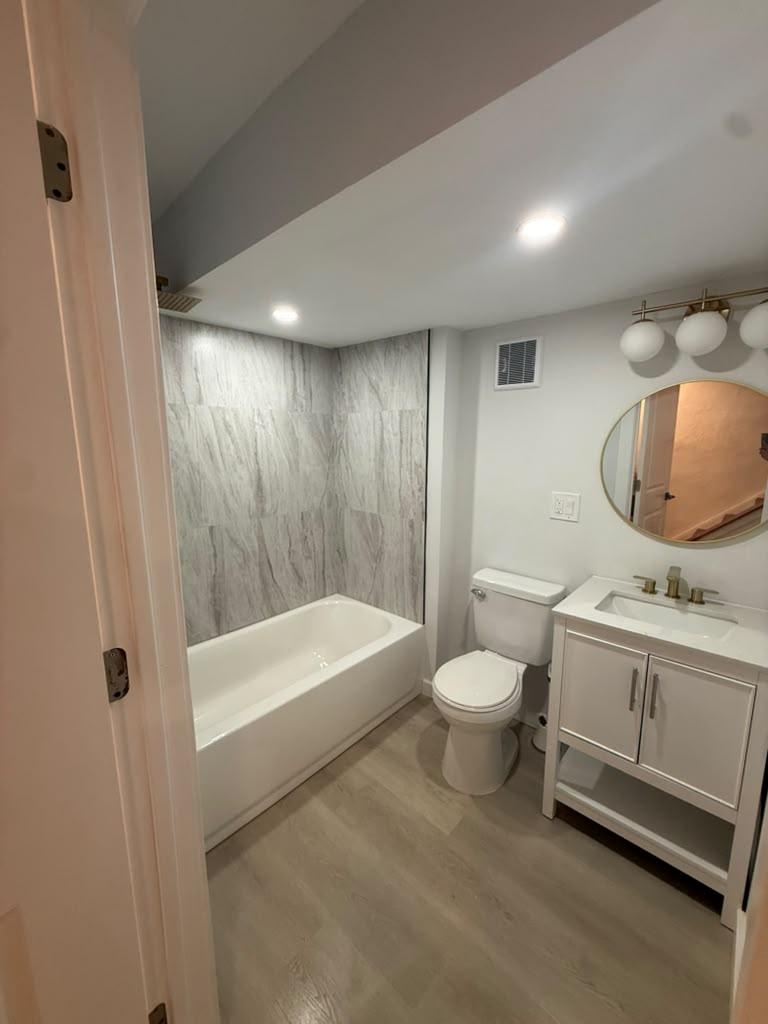 Hall bathroom with tiled tub surround, white vanity, and brass fixtures