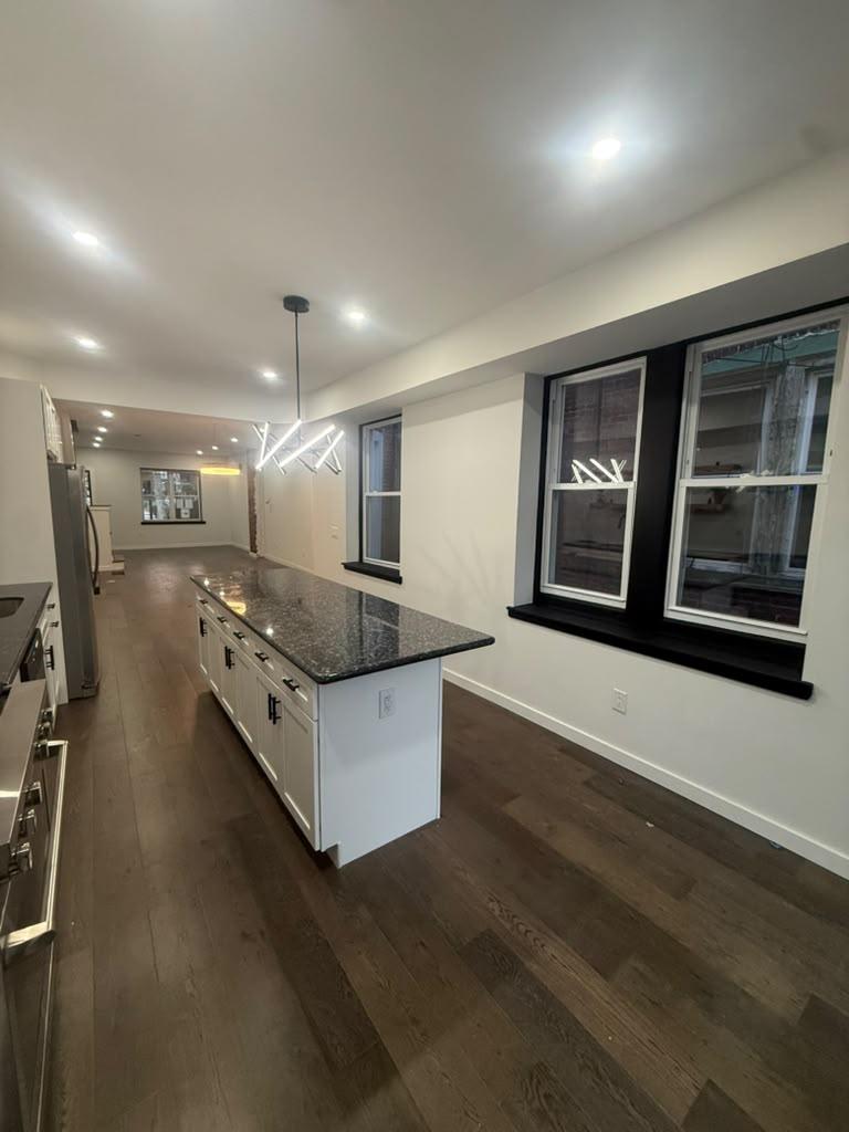 Granite kitchen island beside black-trimmed windows and wide-plank floors