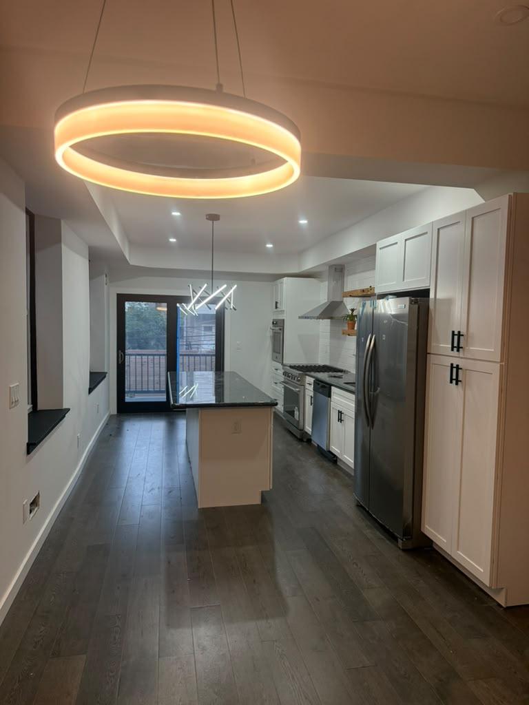 Kitchen and dining area under a ring pendant with glass doors to the deck
