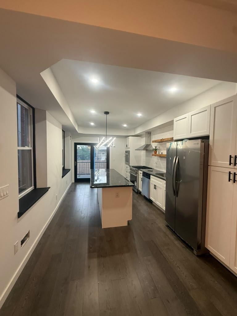 Kitchen with tray ceiling, pantry cabinet wall, and stainless refrigerator