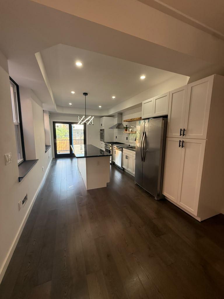 Wide view of the kitchen with tray ceiling and hardwood floors
